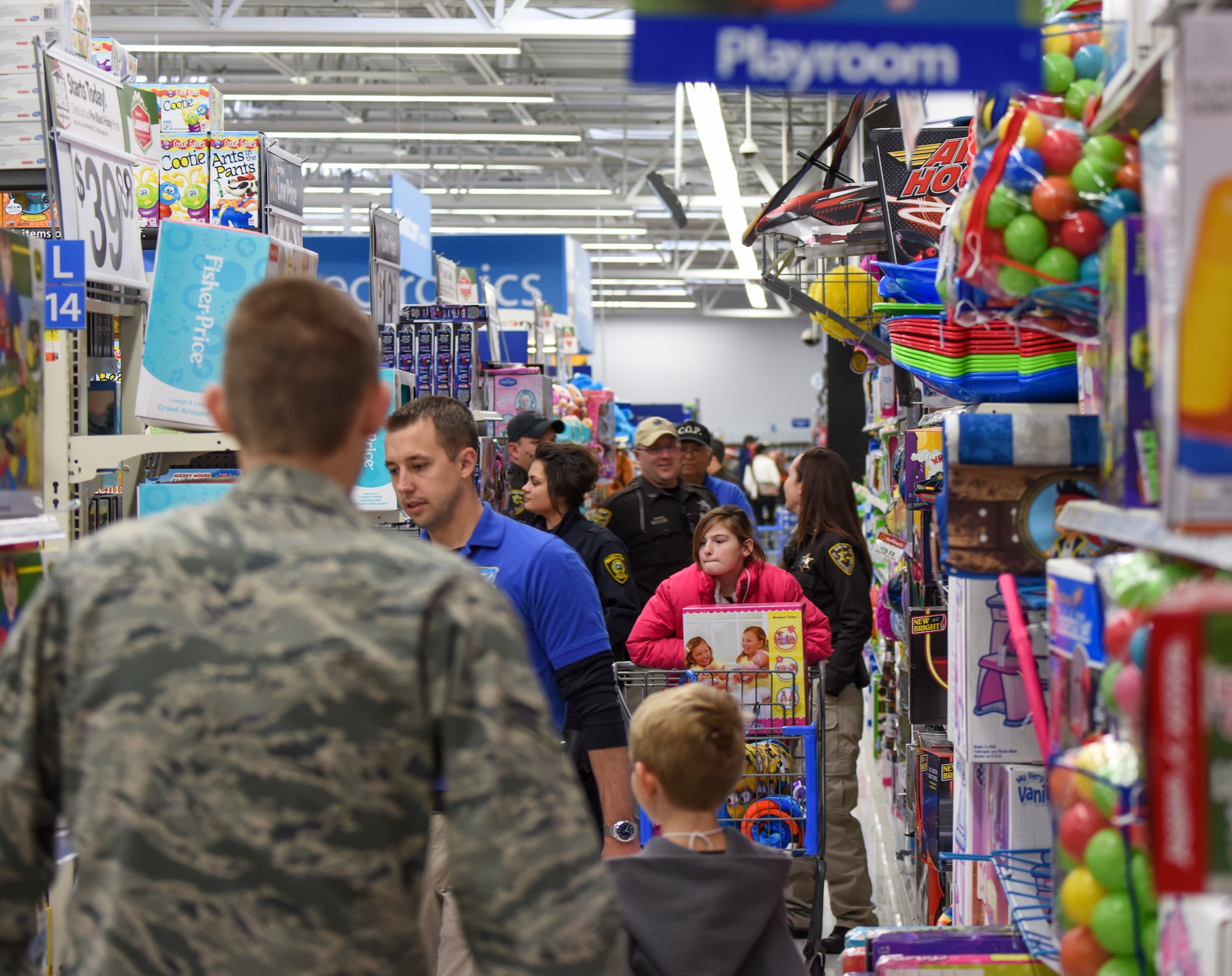 Police officers and their assigned children navigate through crowded aisles during the "Shop with a Cop" event in Mountain Home, Idaho, Dec. 6, 2014. The aisles were full of children trying to find the perfect gift for either themselves or family members. (U.S. Air Force photo by Jeremy L. Mosier/RELEASED)