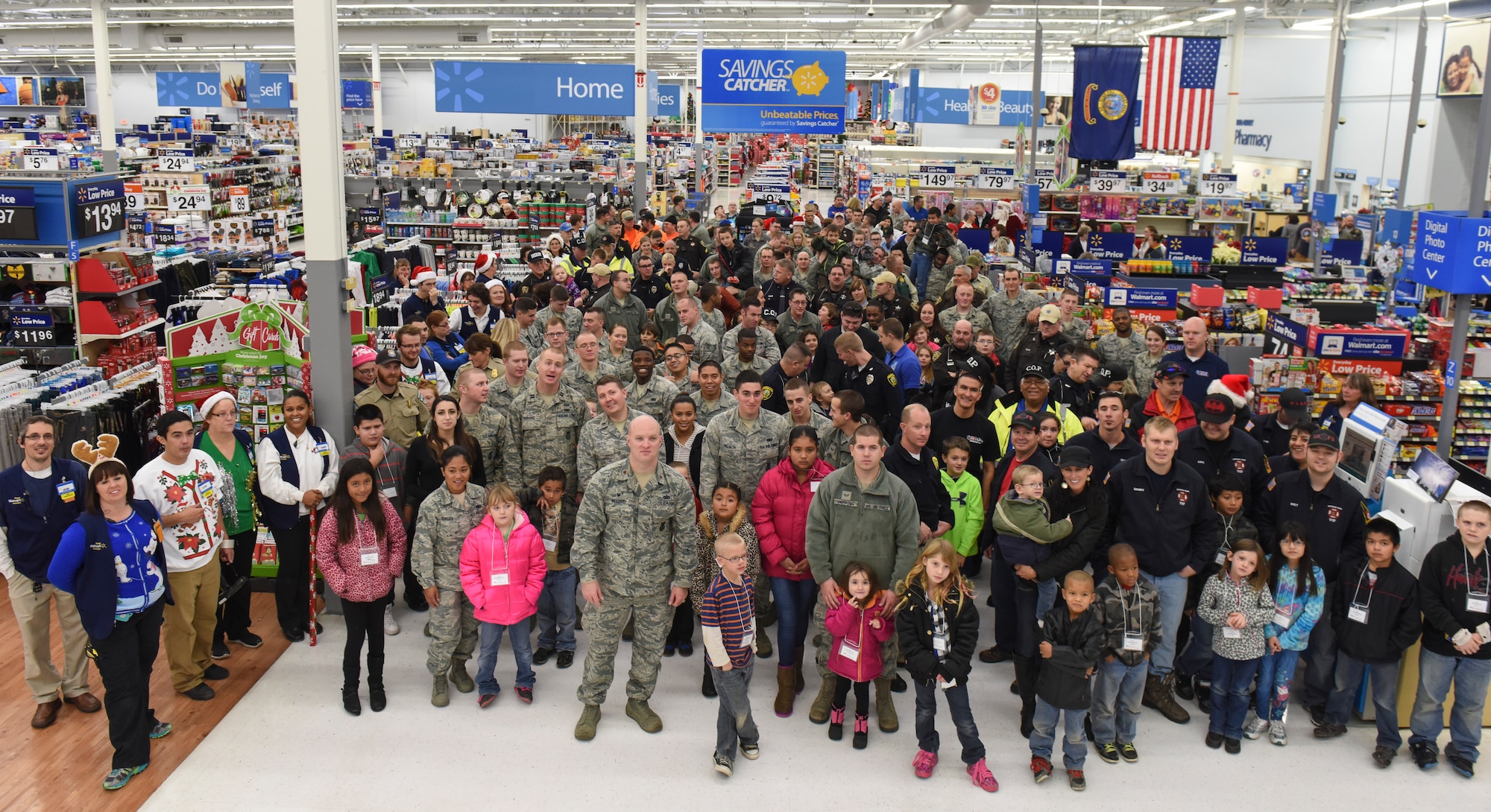 Volunteers and children gather for a group photo before being released to shop in Mountain Home, Idaho, Dec. 6, 2014. After purchasing their gifts, volunteers helped the children wrap the presents before heading home. (U.S. Air Force photo by Jeremy L. Mosier/RELEASED)