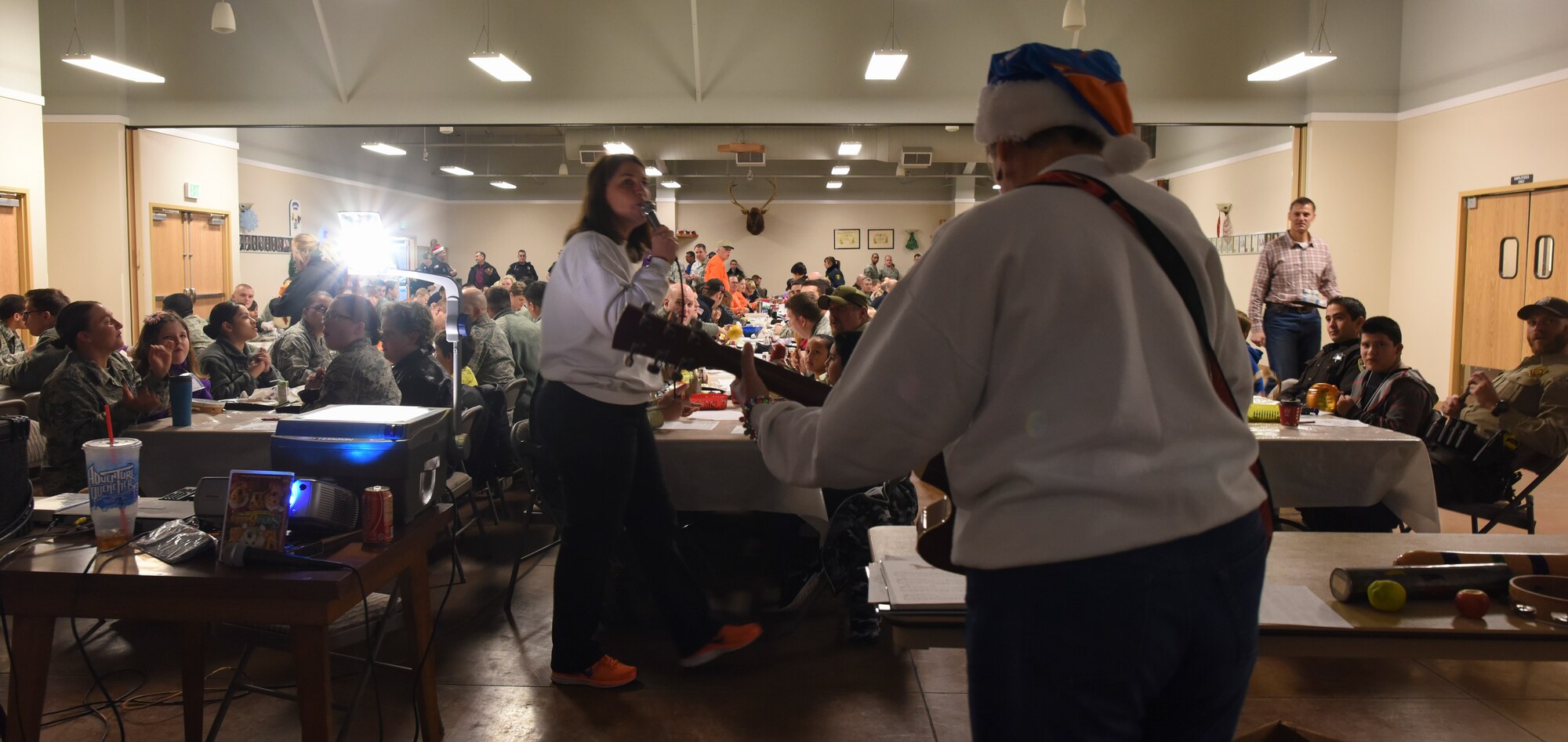 Volunteers lead children in holiday caroling during the "Shop with a Cop" event in Mountain Home, Idaho, Dec. 6, 2014. After caroling, the children boarded a school bus or rode in police cars and headed to the final portion of the day, shopping. (U.S. Air Force photo by Jeremy L. Mosier/RELEASED)