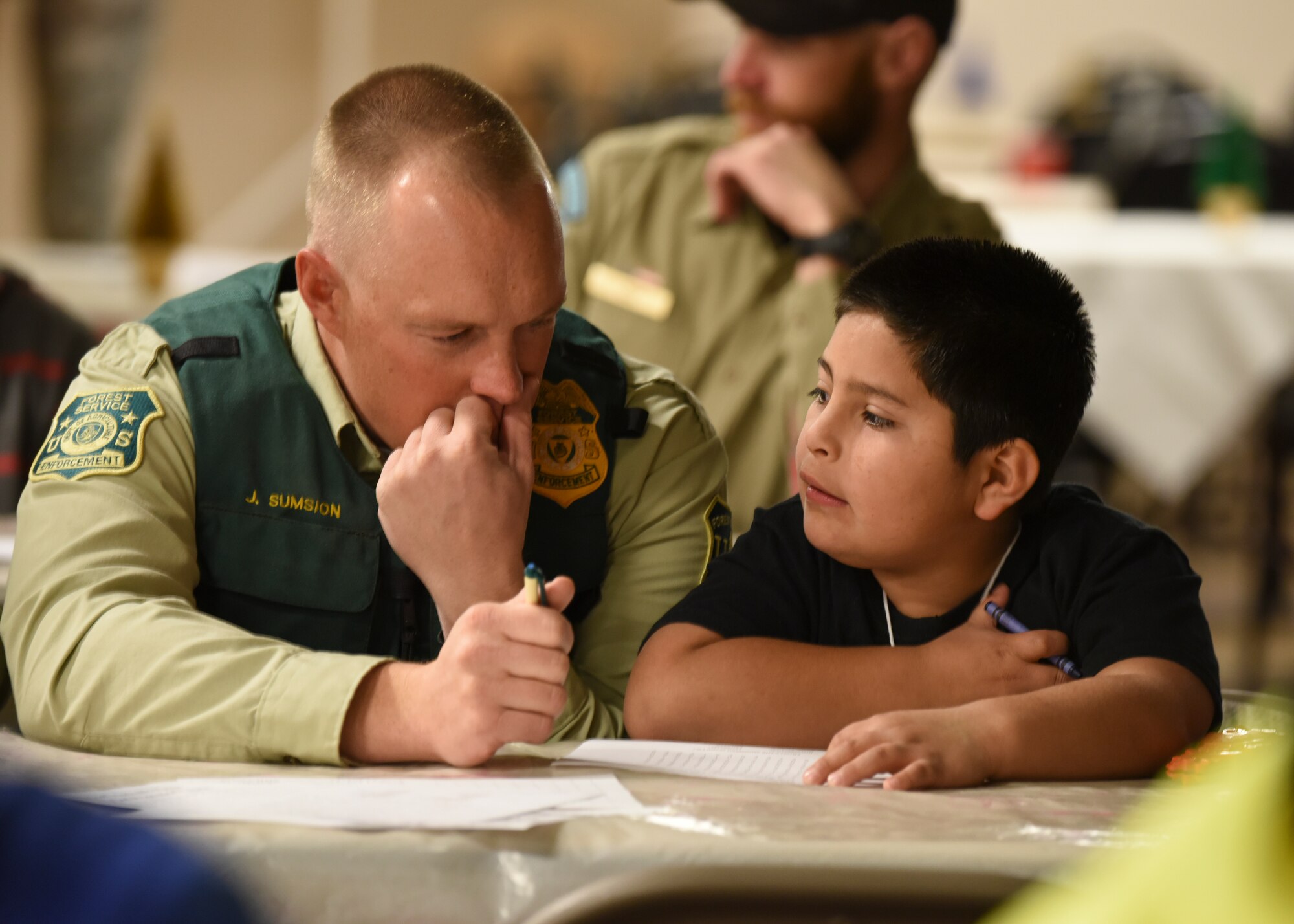 A local police officer colors with a child during the "Shop with a Cop" event in Mountain Home, Idaho, Dec. 6, 2014. During this event children were given the opportunity to interact with local law enforcement during breakfast. (U.S. Air Force photo by Jeremy L. Mosier/RELEASED)