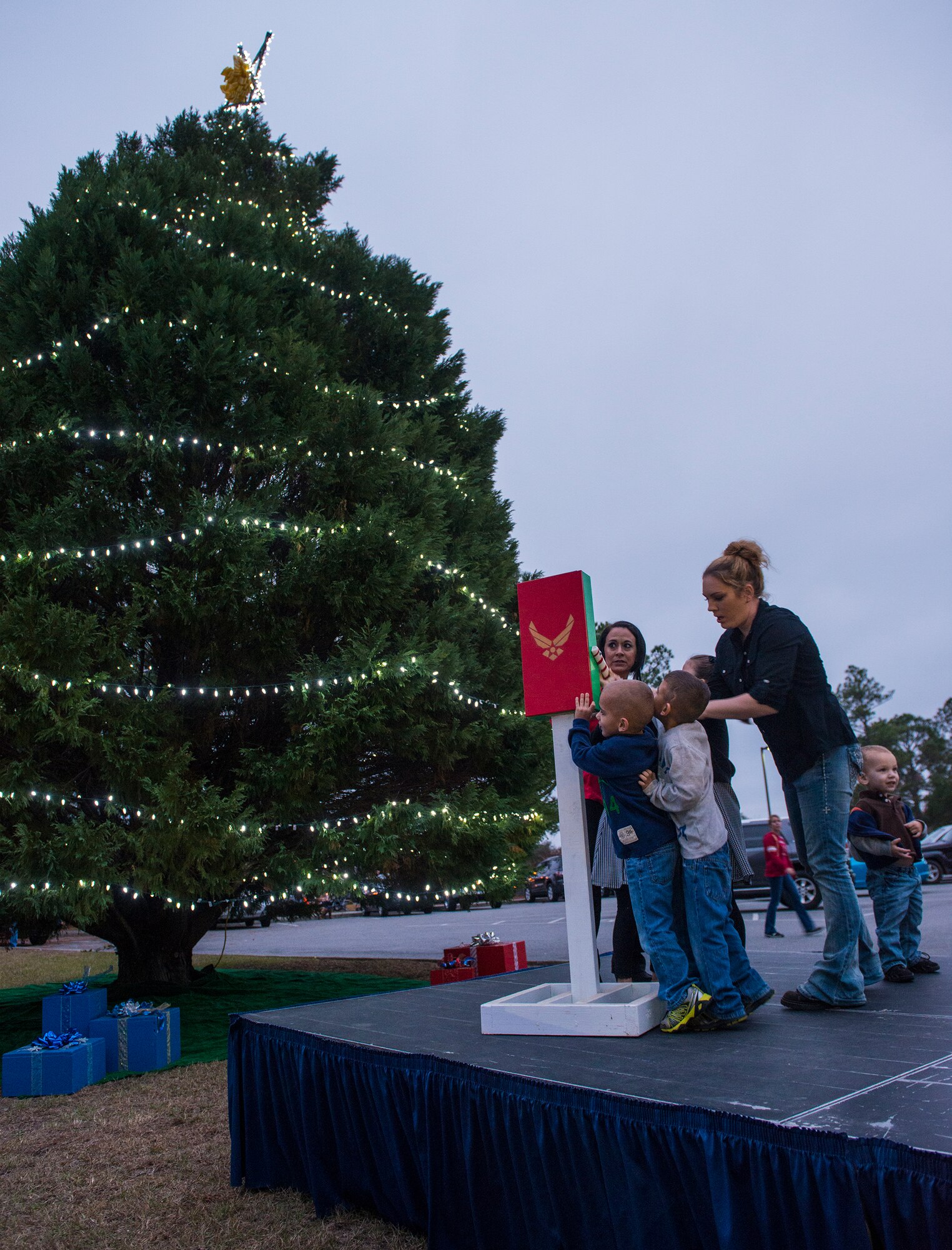 Team Moody members pull the lever to light the tree during the Annual Tree Lighting Ceremony and Holiday Parade Dec. 5, 2014, at Moody Air Force Base, Ga. The Airman Family and Readiness Center selected two families of deployed Airmen to light the tree and to be recognized during the tree lighting ceremony for all of their sacrifices. (U.S. Air Force photo by Airman 1st Class Ceaira Tinsley/Released)