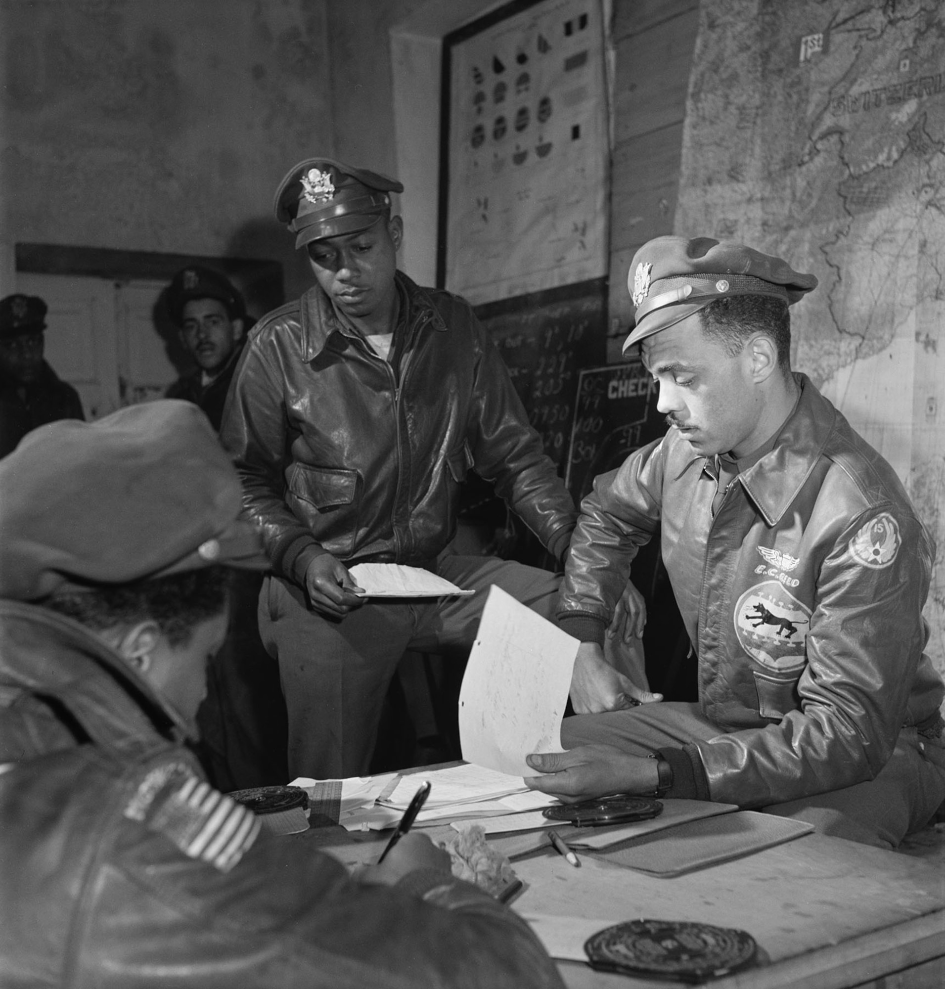 Wearing the jacket on display at the National Museum of the U.S. Air Force, Capt. (later Col.) Edward C. Gleed (right), the 332nd Fighter Group’s operations officer and Lt. (later Lt. Col.) Woodrow W. Crockett (center) plan for a mission in March 1945. Note that Gleed later removed the 15th Air Force emblem from the jacket’s left sleeve. (U.S. Air Force photo)