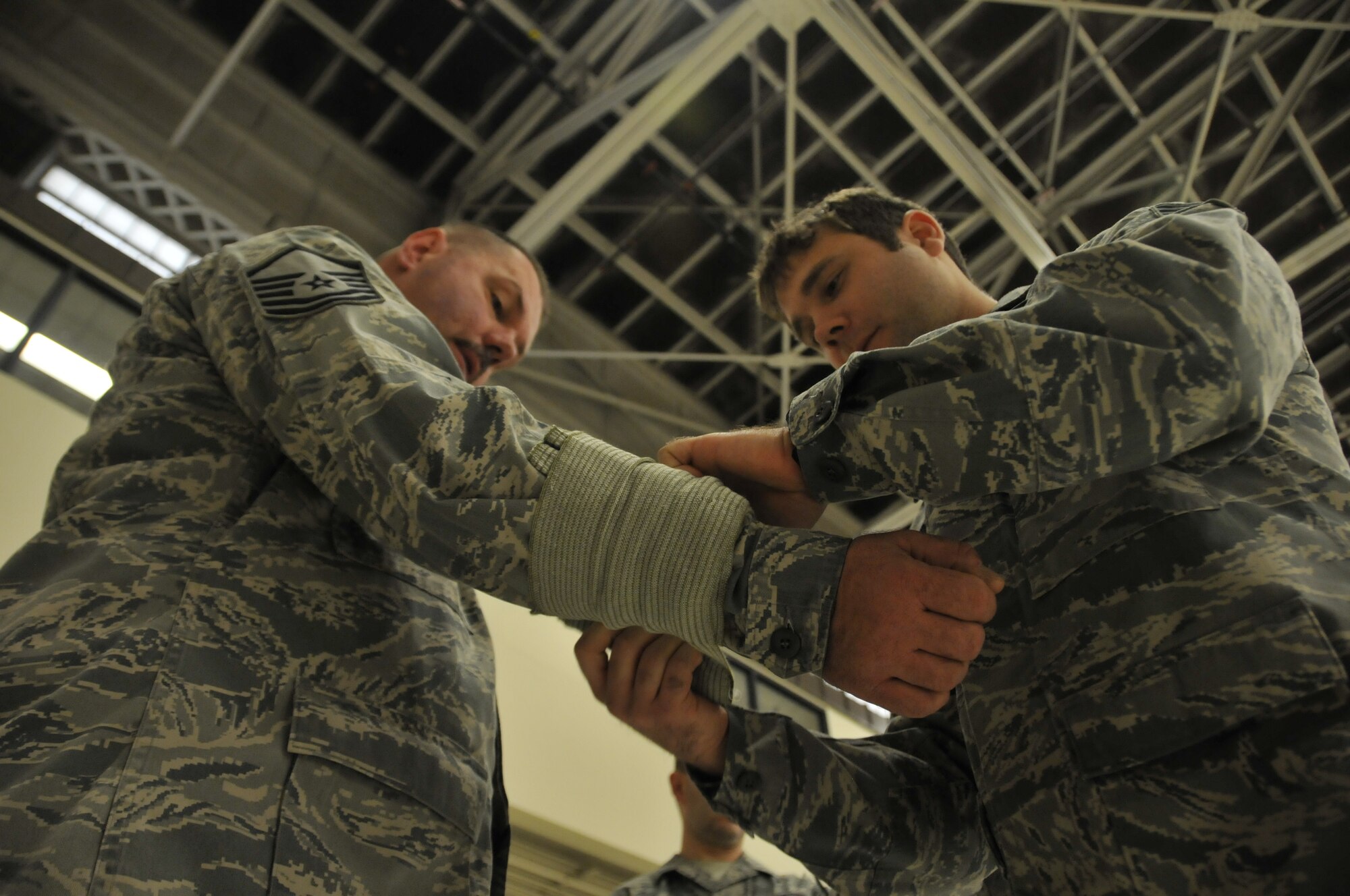 Senior Airman John Barker dresses a simulated wound on Master Sgt. Mike Kolb during an expeditionary skills rodeo held at Ebbing Air National Guard Base, Fort Smith, Ark., Dec. 7. The event was designed to refresh the members’ chemical survival and self-aid buddy care skills. Barker is assigned to the 123rd Intelligence Squadron and is assigned to the 153rd IS. (U.S. Air National Guard photo by Staff Sgt. John Suleski/Released)