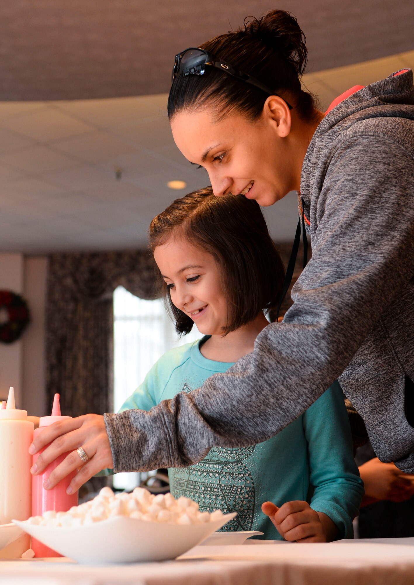 U.S. Army Sgt. Melissa Raposo, 359th Inland Cargo Transportation Company, 10th Transportation Battalion, 7th Transportation Brigade (Expeditionary) squad leader, and her daughter, Haley, decorate cookies during Breakfast with Santa at Fort Eustis, Va., Dec. 6, 2014. In addition to cookie decorations, children watched movies, talked to Santa, made decorations and more. (U.S. Air Force photo by Senior Airman Austin Harvill/Released)