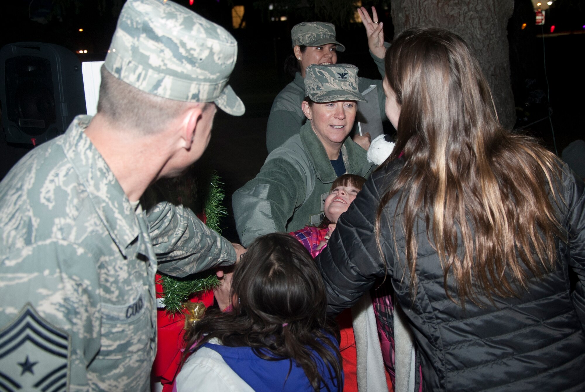 Col. Tracey Hayes, 90th Missile Wing commander, and Chief Master Sgt. Samuel Couch, 90th MW command chief, joined by children from base, pull a lever to light the holiday tree Dec. 5 during the annual tree lighting ceremony. 
