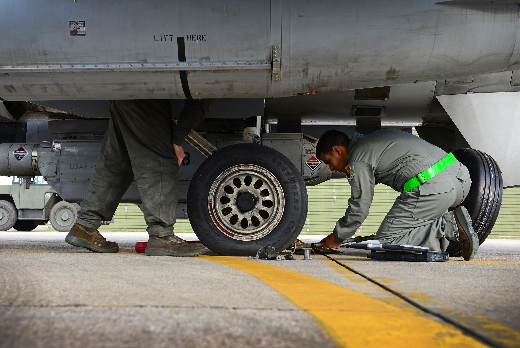 (From left) Airmen 1st Class Juanluis Cota and Alexis Garrido, 31st Maintenance Squadron crew chiefs, change an F-16 Fighting Falcon’s tire, Dec. 9, 2014, at Aviano Air Base, Italy. Last week operations and maintenance Airmen joined together to successfully fly over 300 sorties during the first surge week of the fiscal year. (U.S. Air Force photo/Senior Airman Matthew Lotz)