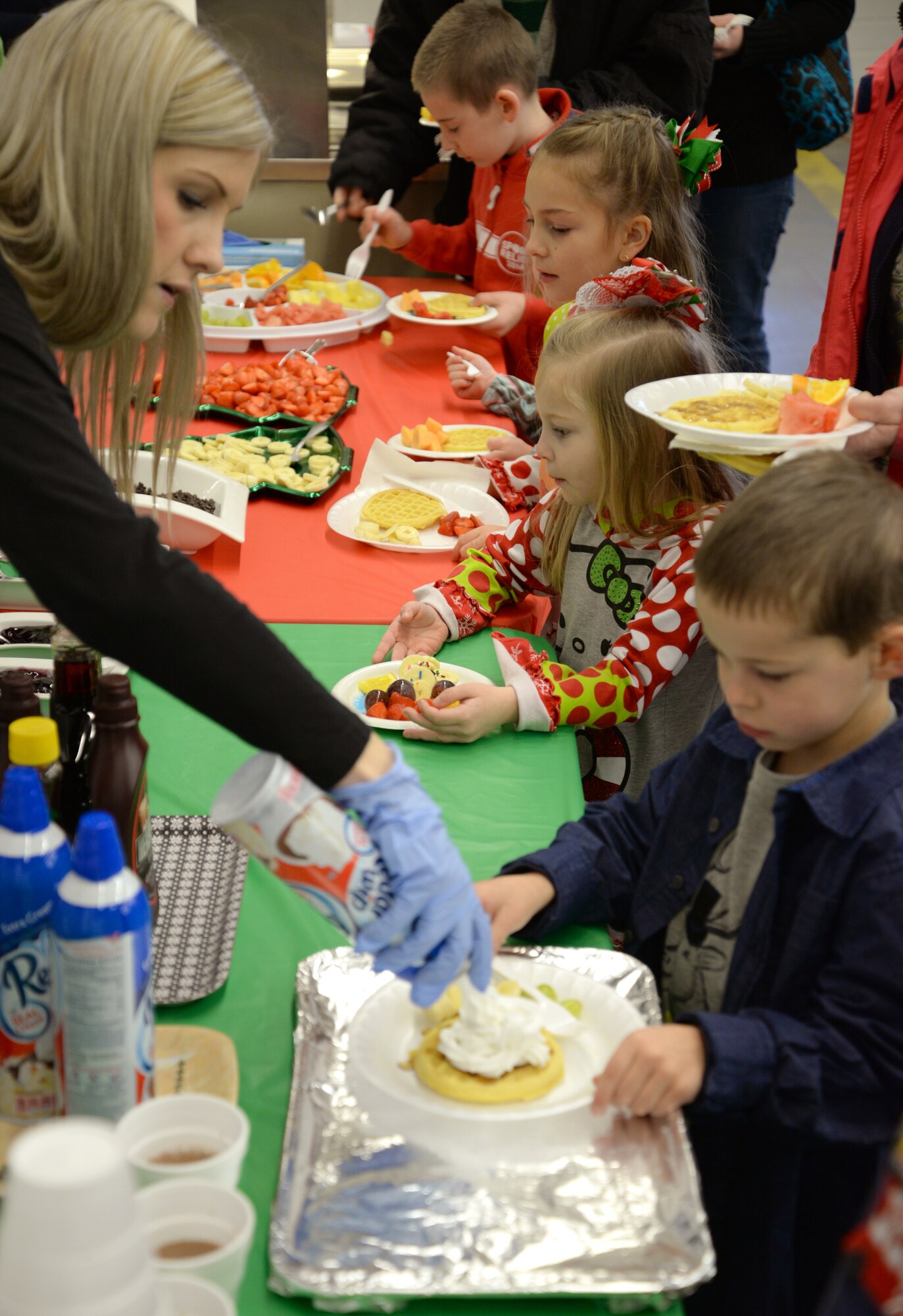 Team Mildenhall children make plates of food during Breakfast with Santa Dec. 6, 2014, on RAF Mildenhall, England. Volunteers handed out waffles, fruit and hot cocoa to the children as they waited for Santa to arrive. (U.S. Air Force photo by Airman 1st Class Dillon Johnston/Released)