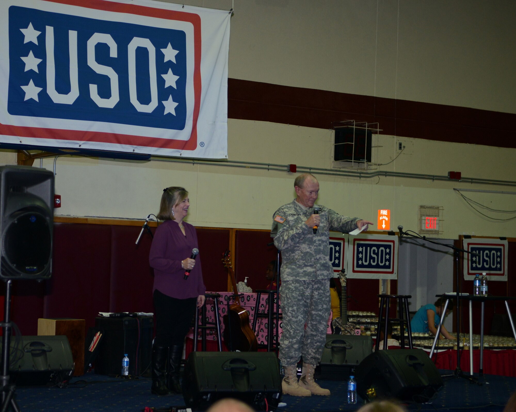 Chairman of the Joint Chiefs of Staff, Army Gen. Martin E. Dempsey and his wife Deanie, speak to those in attendance of a United Service Organizations holiday tour, Dec. 8, 2014, at Incirlik Air Base, Turkey. This tour marks Dempsey’s fourth and final USO tour. He is accompanied by celebrity guests Washington Nationals pitcher Doug Fisher, “Glee” musical drama actress Dianna Agron, comedian Rob Riggle, actress of “Suits” Meghan Markle, country singer Kellie Pickler, and eight-time Pro Bowler/former Chicago Bears linebacker Brian Urlacher.   (U.S. Air Force photo by Staff Sgt. Caleb Pierce/Released)