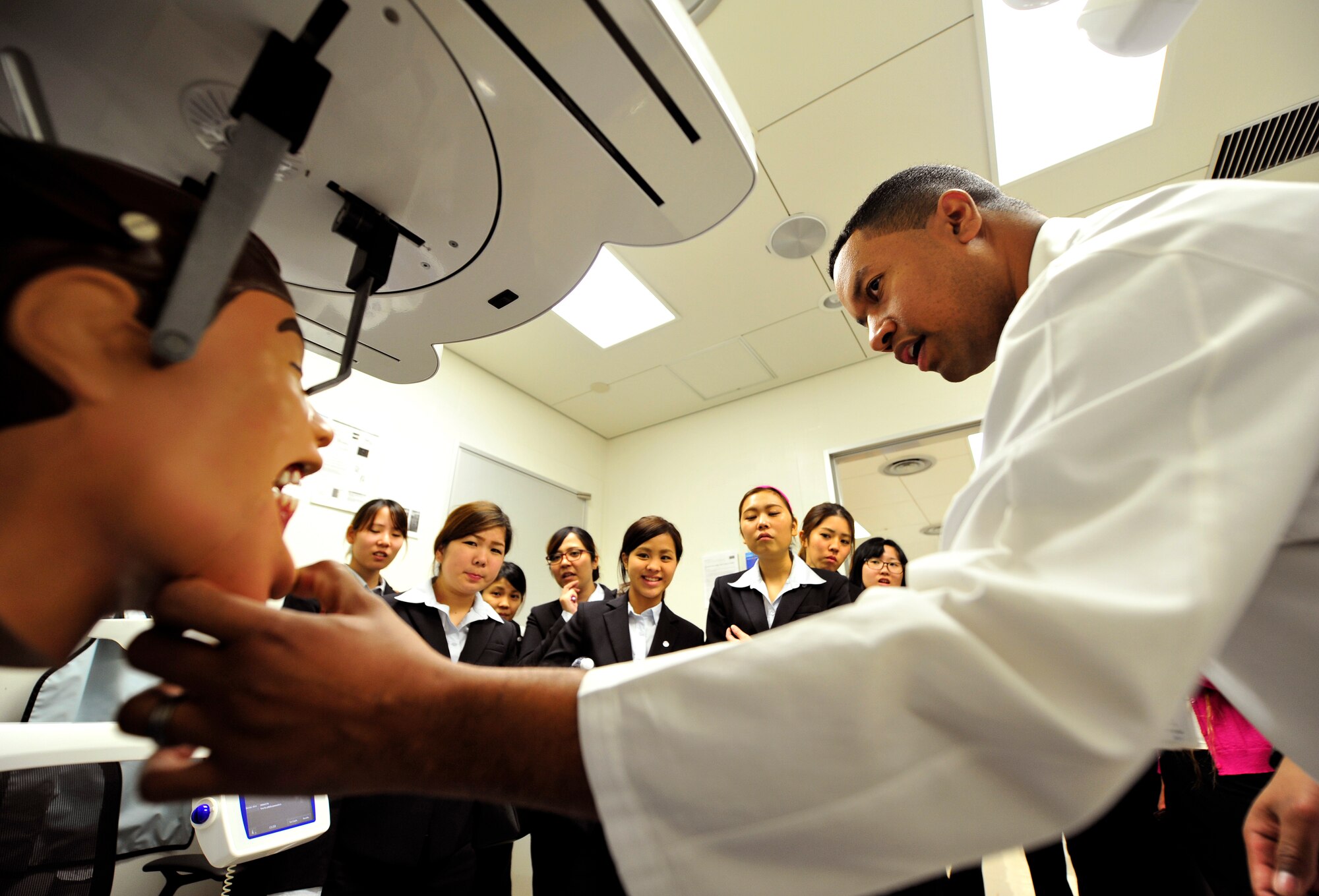 U.S. Air Force Staff Sgt. Robert Penn, 18th Dental Squadron NCO in charge of dental radiology, shows the teeth of a mannequin to local dental hygiene students during a tour of the dental clinic facility on Kadena Air Base, Japan, Dec. 5, 2014. The visit provided a way for Okinawans to interact with active duty members, a professional exchange of ideas and patient related treatment options. (U.S. Air Force photo by Naoto Anazawa/Released)