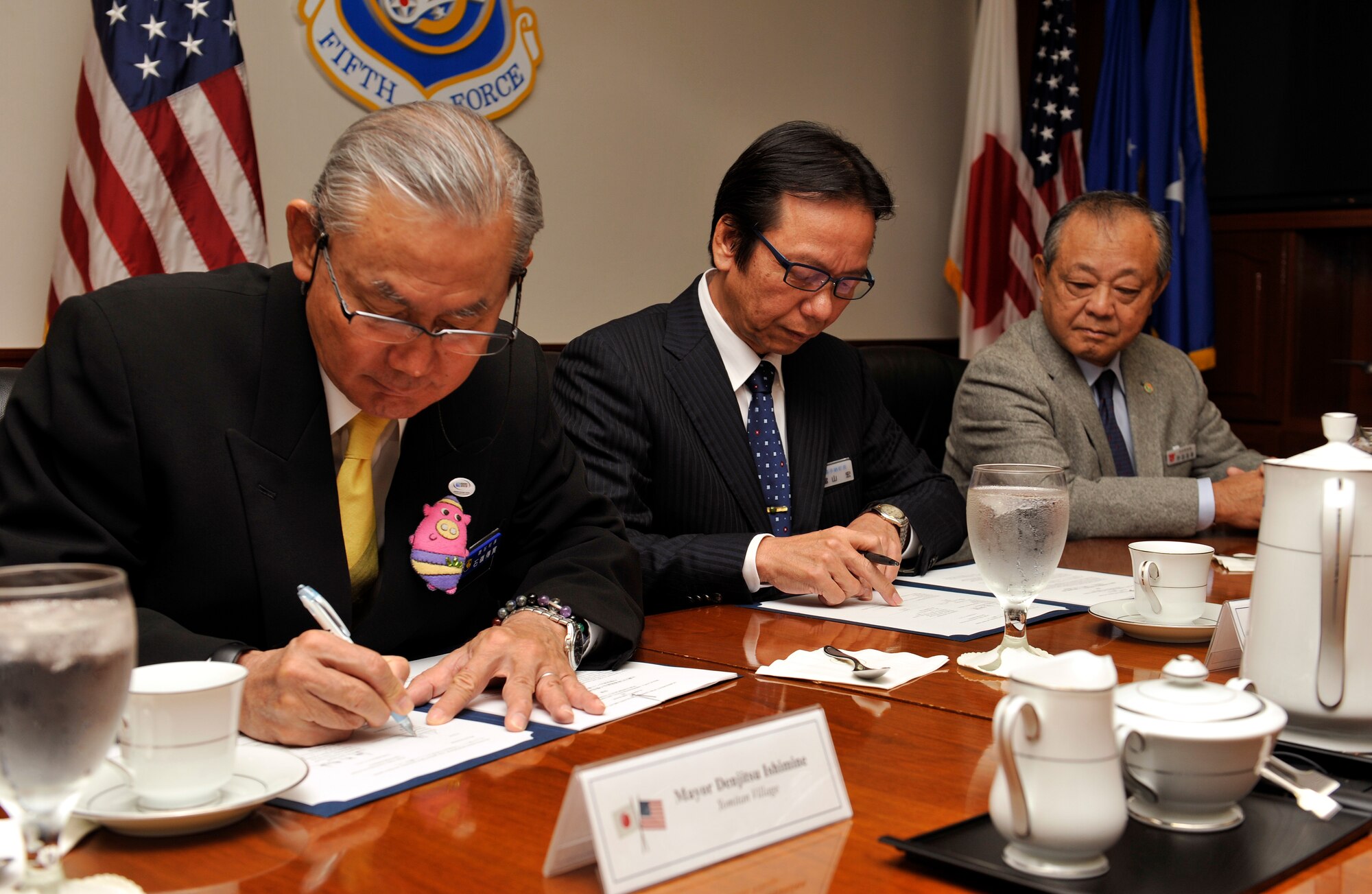 Denjitsu Ishimine, mayor of Yomitan Village, Hiroshi Toyama, mayor of Kadena Town, and Masaharu Noguni, mayor of Chatan Town, sign a letter of agreement for Limited Humanitarian Access to Kadena Air Base during a signing ceremony on Kadena Air Base, Japan, Dec. 5, 2014. This letter of agreement allows emergency vehicles from Yomitan Village, Kadena Town and Chatan Town to access Kadena Air Base to respond quickly to save lives. (U.S. Air Force photo by Naoto Anazawa/Released)