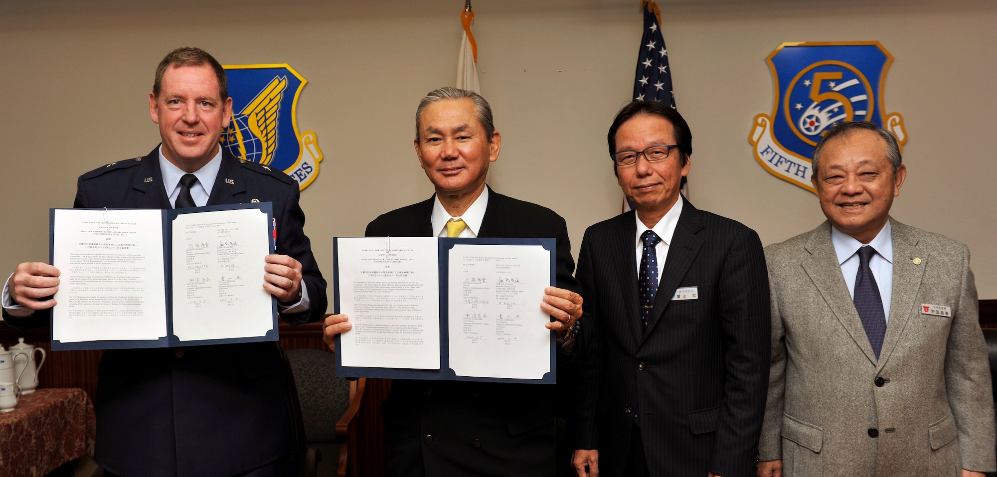 U.S. Air Force Brig. Gen. James Hecker, 18th Wing commander, Denjitsu Ishimine, mayor of Yomitan Village, Hiroshi Toyama, mayor of Kadena Town and Masaharu Noguni, mayor of Chatan Town take a group photo after signing the Limited Humanitarian Access letter on Kadena Air Base, Japan, Dec. 5, 2014. This letter of agreement allows emergency vehicles from Yomitan Village, Kadena Town and Chatan Town to access Kadena Air Base to respond quickly to save lives. (U.S. Air Force photo by Naoto Anazawa/Released)