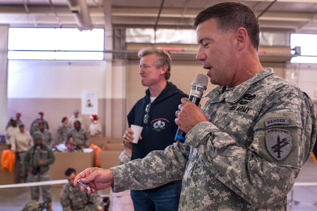 Army Maj. Gen. Daniel R. Ammerman, commander, United States Army Civil Affairs and Psychological Operations Command Airborne, reads off a lottery ticket number at 17th Annual Randy Oler Memorial Operation Toy Drop, at Green Ramp, Pope Army Airfield, Fort Bragg, N.C., Dec. 5, 2014.