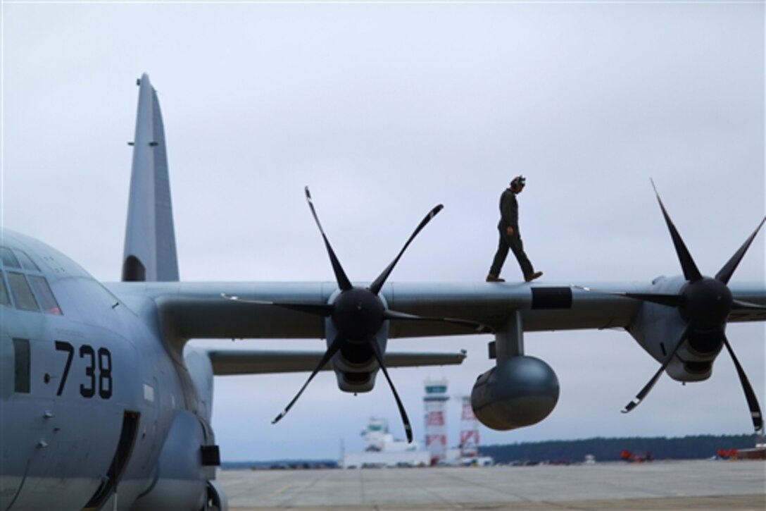 Marine Corps Staff Sgt. Christopher T. Macheimer walks on the wing of a KC-130 Hercules aircraft performing preflight checks on Marine Corps Air Station Cherry Point, N.C., Dec. 2, 2014. Macheimer is a crew master assigned to Marine Aerial Refueler Transport Squadron 252.