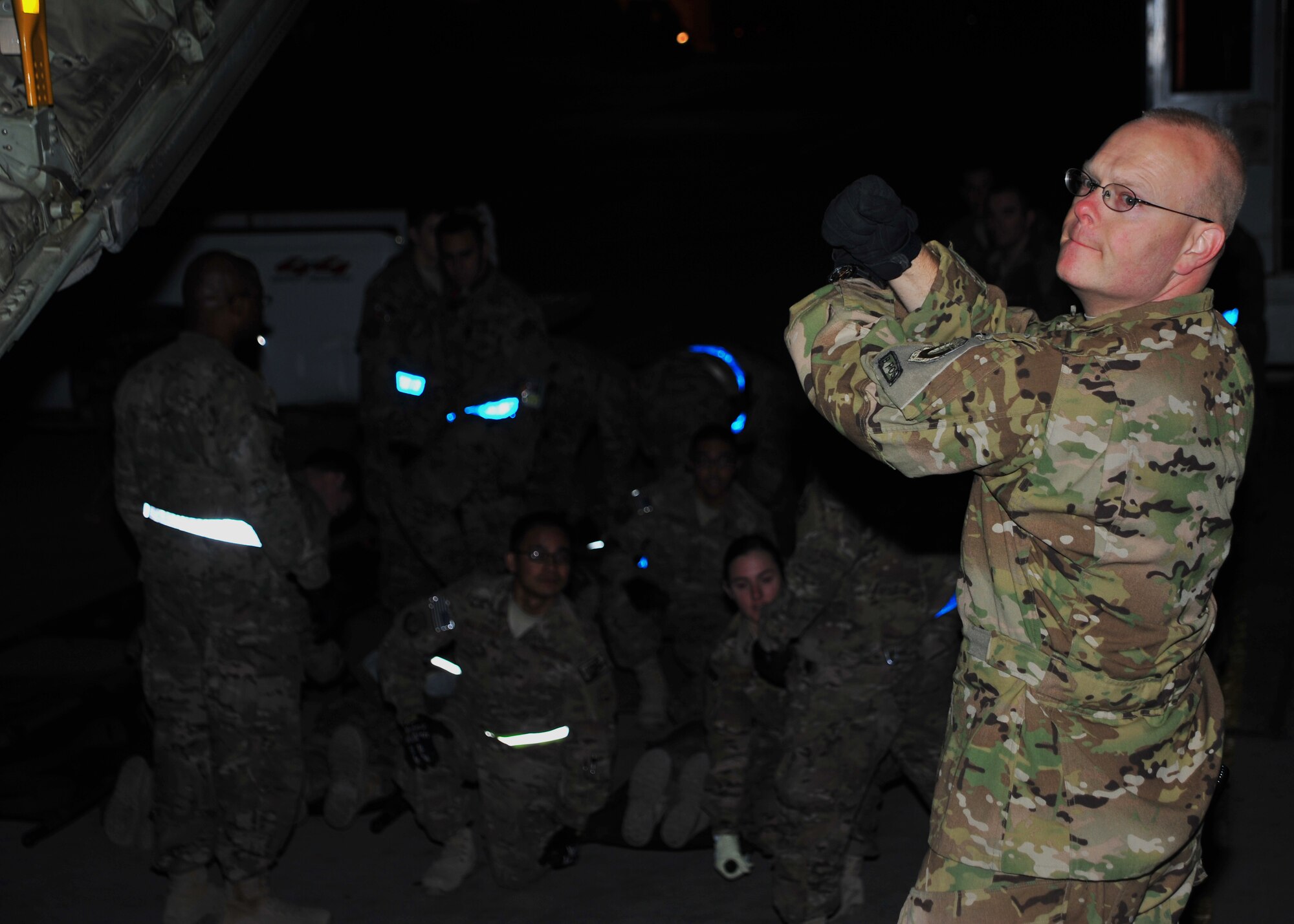 U.S. Air Force Lt. Col. Christopher Day, 455th Expeditionary Aeromedical Evacuation Squadron, communicates with a waiting litter team with hand signal during a training scenario Dec. 6, 2014. Once given the go-ahead, the team will lift, move, halt and lower the litter in unison, following the commands of the team lead. (U.S. Air Force photo by Staff Sgt. Whitney Amstutz/released)