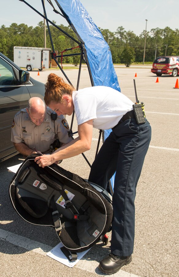 Susanna Williams, training division chief with Jacksonville Fire and Emergency Services, and Sgt. Randall Butler, with the Onslow County Sheriff's Office inspect a car seat at Base Safety Division’s quarterly Child Passenger Safety Seat Check at the parking lot of the Marine Corps Exchange aboard Marine Corps Base Camp Lejeune, May 19 to 21. Representatives certified by the National Highway Traffic Safety Administration, including members of Jacksonville’s Fire and Emergency Services, Onslow County Sheriff's Office, N.C. State Highway Patrol, the Provost Marshal’s Office and the Base Safety Division, conducted the checks.