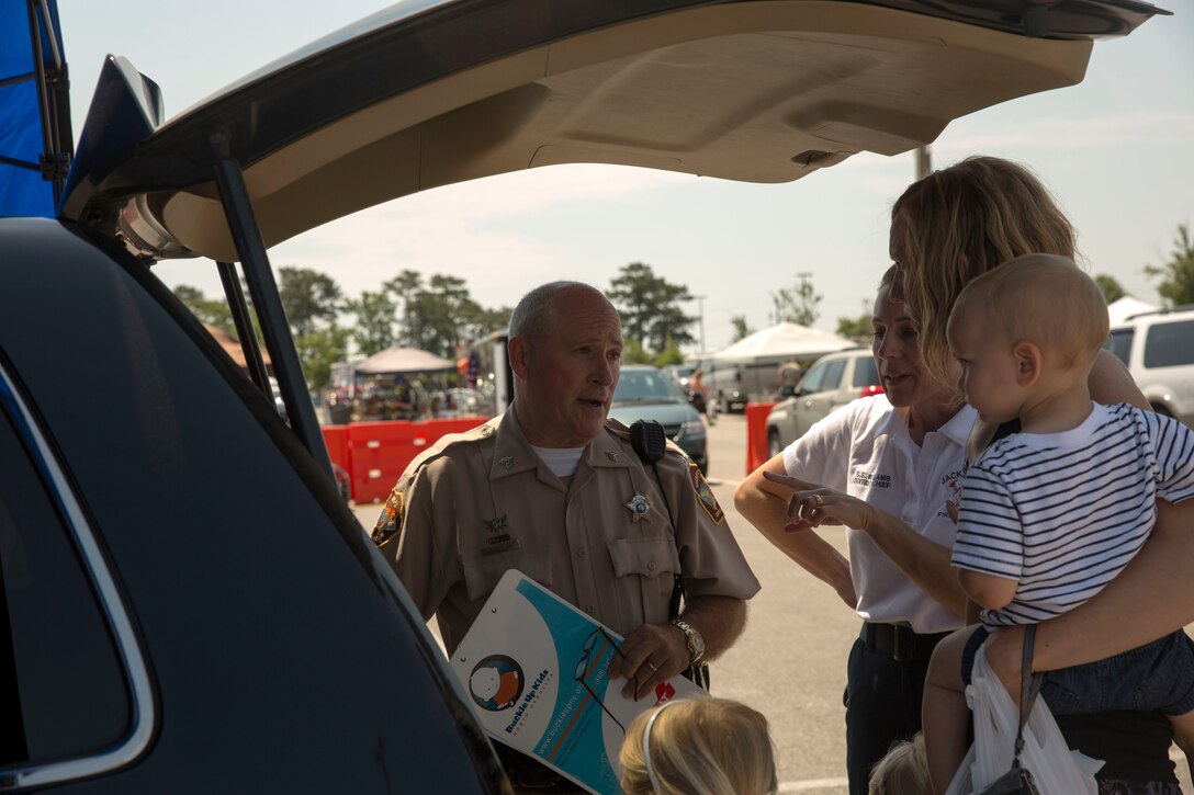 Sgt. Randall Butler, with the Onslow County Sheriff's Office speaks to a parent at Base Safety Division’s quarterly Child Passenger Safety Seat Check at the parking lot of the Marine Corps Exchange aboard Marine Corps Base Camp Lejeune, May 19 to 21. Representatives certified by the National Highway Traffic Safety Administration, including members of Jacksonville’s Fire and Emergency Services, Onslow County Sheriff's Office, N.C. State Highway Patrol, the Provost Marshal’s Office and the Base Safety Division, conducted the checks.