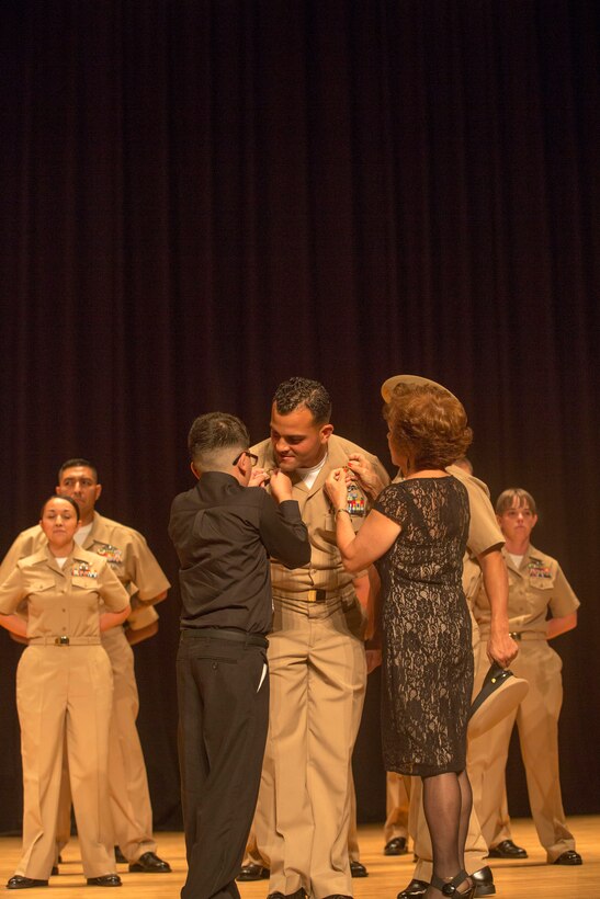 Chief Petty Officer Ariel Ampier is pinned by Kaynen and Inid Maldonado during his induction ceremony, at the base theater aboard the Marine Corps Base Camp Lejeune, September 16. Twenty-two sailors from area units earned the promotion to E-7 after undergoing testing, a selection board and a six-week induction program.