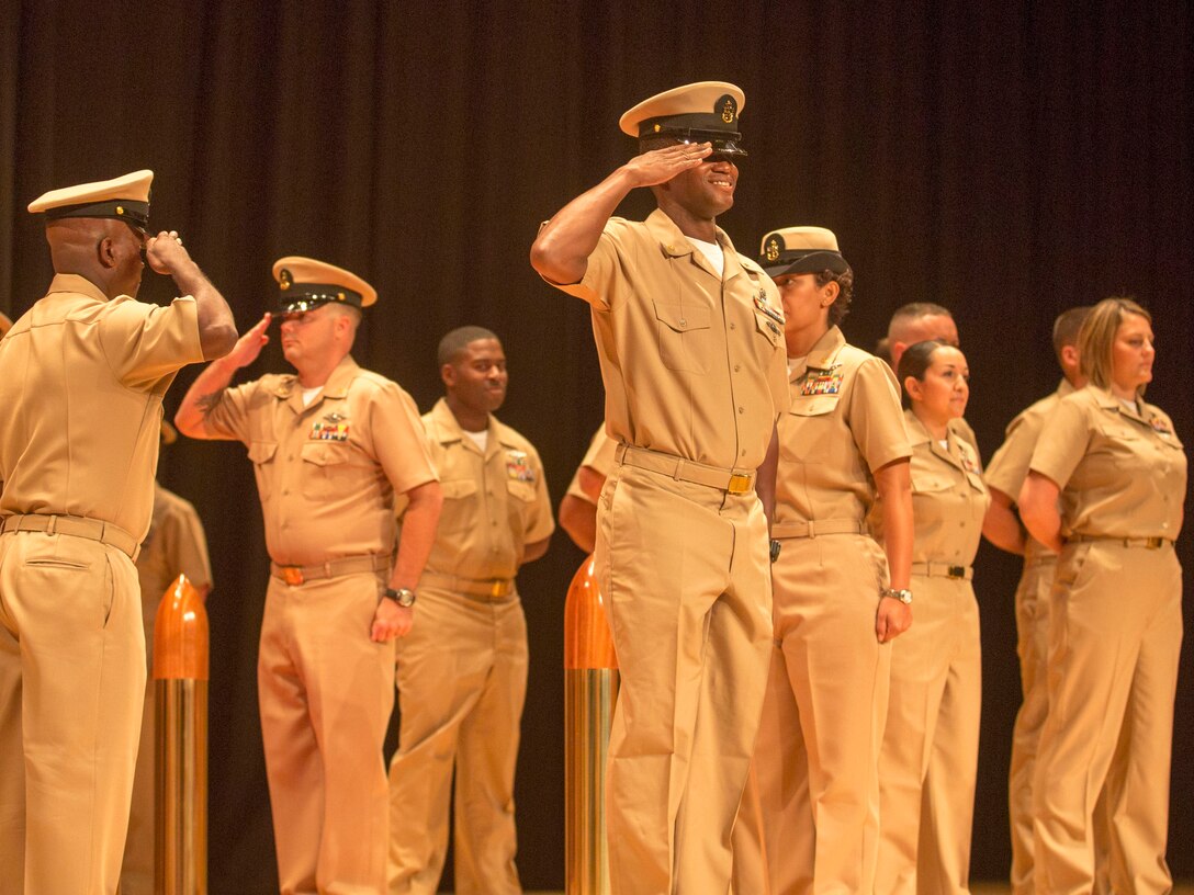 A new chief petty officer salutes after making his way past his peers and a group of sideboys during his induction ceremony, at the base theater aboard the Marine Corps Base Camp Lejeune, September 16. Twenty-two sailors from area units earned the promotion to E-7 after undergoing testing, a selection board and a six-week induction program.