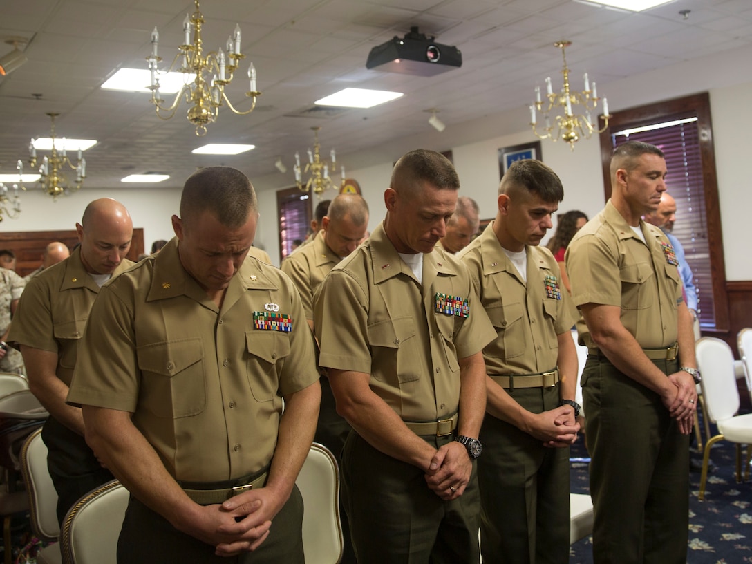 Students with Camp Lejeune’s inaugural Command and Staff College Blended Seminar Program, bow their heads during a prayer at the course’s graduation ceremony held at the Officers’ Club aboard Marine Corps Base Camp Lejeune, Sept. 4. The Command and Staff College Blended Seminar Program is a distance professional military education course for Chief Warrant Officer 4, Marine field grade and other service field grade officers. The course offers instruction in the small wars, joint warfighting, amphibious operations and operational planning, among a slew of courses designed to prepare field grade officers for higher level billets. The 10 students were the first graduates of the blended seminar on the East Coast, a similar course was offered in the West Coast which concluded around the same time. Blended seminars are a new approach to distance education, where students participate in periods of focused education with daily classes and periods of online lessons.