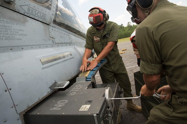 Lance Cpl. Michael Trentman, an aviation ordnance technician with Marine Light Attack Helicopter Squadron 269, feeds rounds into an AH-1W Super Cobra helicopter while Cpl. Kevin Gunther, a team leader with HMLA-269 cranks a device to draw in the rounds during Forward Arming and Refueling Point exercises at Marine Corps Outlying Field Camp Davis, near Holly Ridge, N.C., July 8. Throughout the week the Marines with HLMA-269 filled and reloaded aircraft 18 times with 200 to 300 gallons of fuel each time.