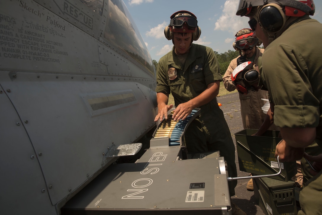 Lance Cpl. Michael Trentman, an aviation ordnance technician with Marine Light Attack Helicopter Squadron 269, feeds rounds into an AH-1W Super Cobra helicopter while Cpl. Kevin Gunther, a team leader with HMLA-269 cranks a device to draw in the rounds during Forward Arming and Refueling Point exercises at Marine Corps Outlying Field Camp Davis, near Holly Ridge, N.C., July 8. Throughout the week the Marines with HLMA-269 filled and reloaded aircraft 18 times with 200 to 300 gallons of fuel each time.