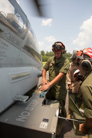 Lance Cpl. Michael Trentman, an aviation ordnance technician with Marine Light Attack Helicopter Squadron 269, feeds rounds into an AH-1W Super Cobra helicopter while Cpl. Kevin Gunther, a team leader with HMLA-269 cranks a device to draw in the rounds during Forward Arming and Refueling Point exercises at Marine Corps Outlying Field Camp Davis, near Holly Ridge, N.C., July 8. Throughout the week the Marines with HLMA-269 filled and reloaded aircraft 18 times with 200 to 300 gallons of fuel each time.