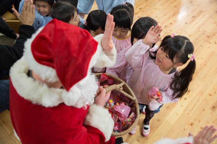 A volunteer from Marine Corps Air Station Iwakuni, Japan, dressed as Santa Claus, hands out candy to the children at Josho Hoikuen during a community relations preschool visit, Dec. 9, 2014. The purpose of this event was to interact with the local community in a gesture of goodwill and strengthen the bond between the U.S. and Japan.