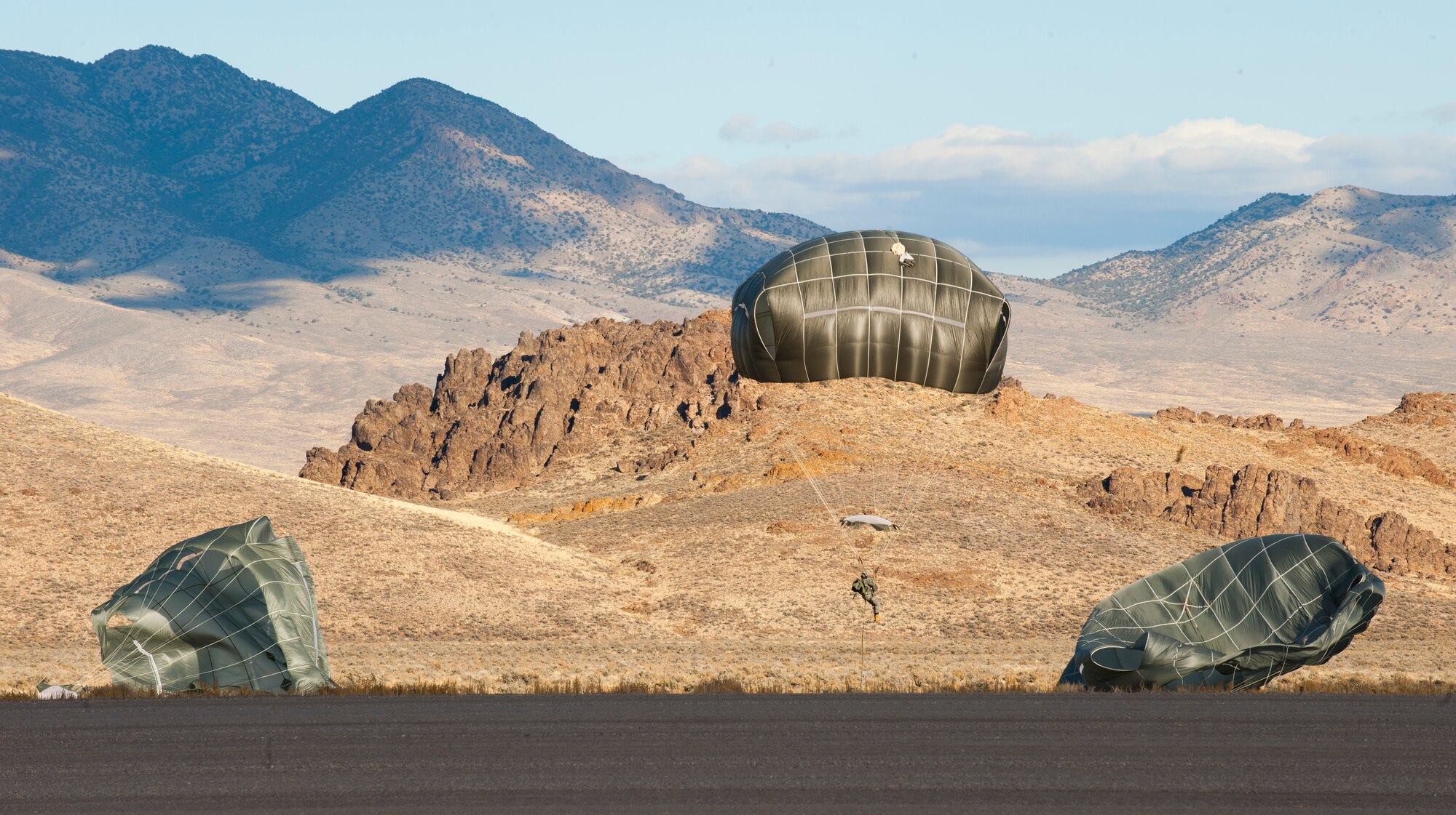 Paratroopers assigned to the 3rd Brigade Combat Team, 82nd Airborne Division, Fort Bragg, N.C., arrive at their drop zone after a jump during the U.S. Air Force Weapons School's Joint Forcible Entry Exercise 14B over the Nevada Test and Training Range Dec. 6, 2014. The NTTR encompasses approximately 2.9 million acres in southern Nevada, and provides a realistic simulated battlespace for joint-service warfighters. (U.S. Air Force photo by Airman First Class Joshua Kleinholz)