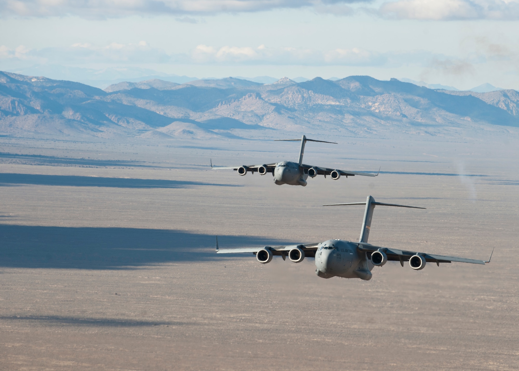 Two U.S. Air Force C-17 Globemaster IIIs fly in formation over the Nevada Test and Training Range to participate in the U.S. Air Force Weapons School's Joint Forcible Entry Exercise 14B Dec. 6, 2014. JFEX, as part of a restructured integration phase in the USAFWS, is a prime example of the advanced training students receive throughout the course that is unmatched anywhere else in the world. (U.S Air Force photo by Senior Airman Thomas Spangler)