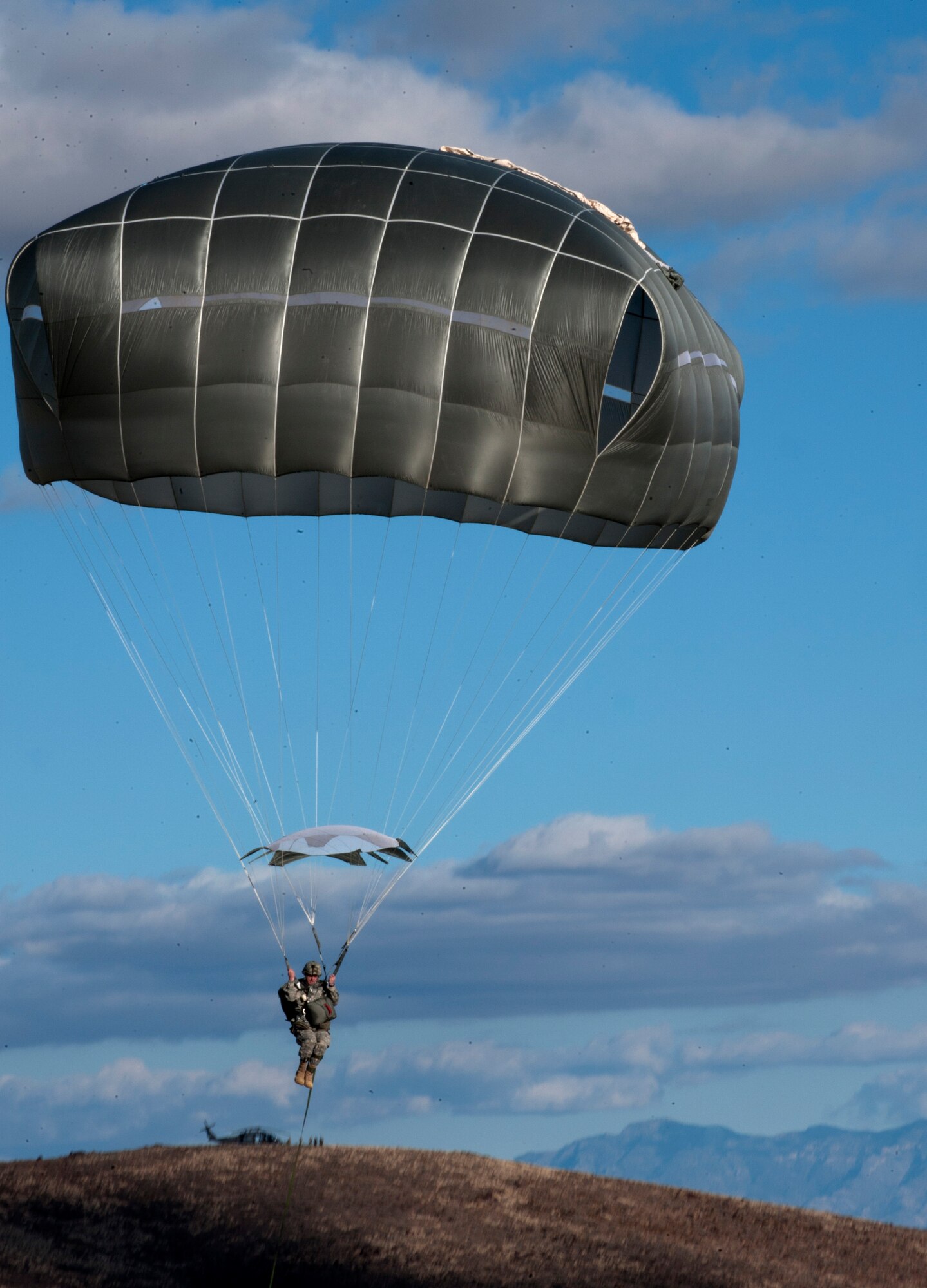 A paratrooper assigned to the 3rd Brigade Combat Team, 82nd Airborne Division, Fort Bragg, N.C., glides to a landing during the U.S. Air Force Weapons School's Joint Forcible Entry Exercise 14B on the Nevada Test and Training Range Dec. 6, 2014. JFEX, as part of a restructured integration phase in the USAFWS, is a prime example of the advanced training students receive throughout this course that is unmatched anywhere else in the world. (U.S. Air Force photo by Staff Sgt. Victoria Sneed)