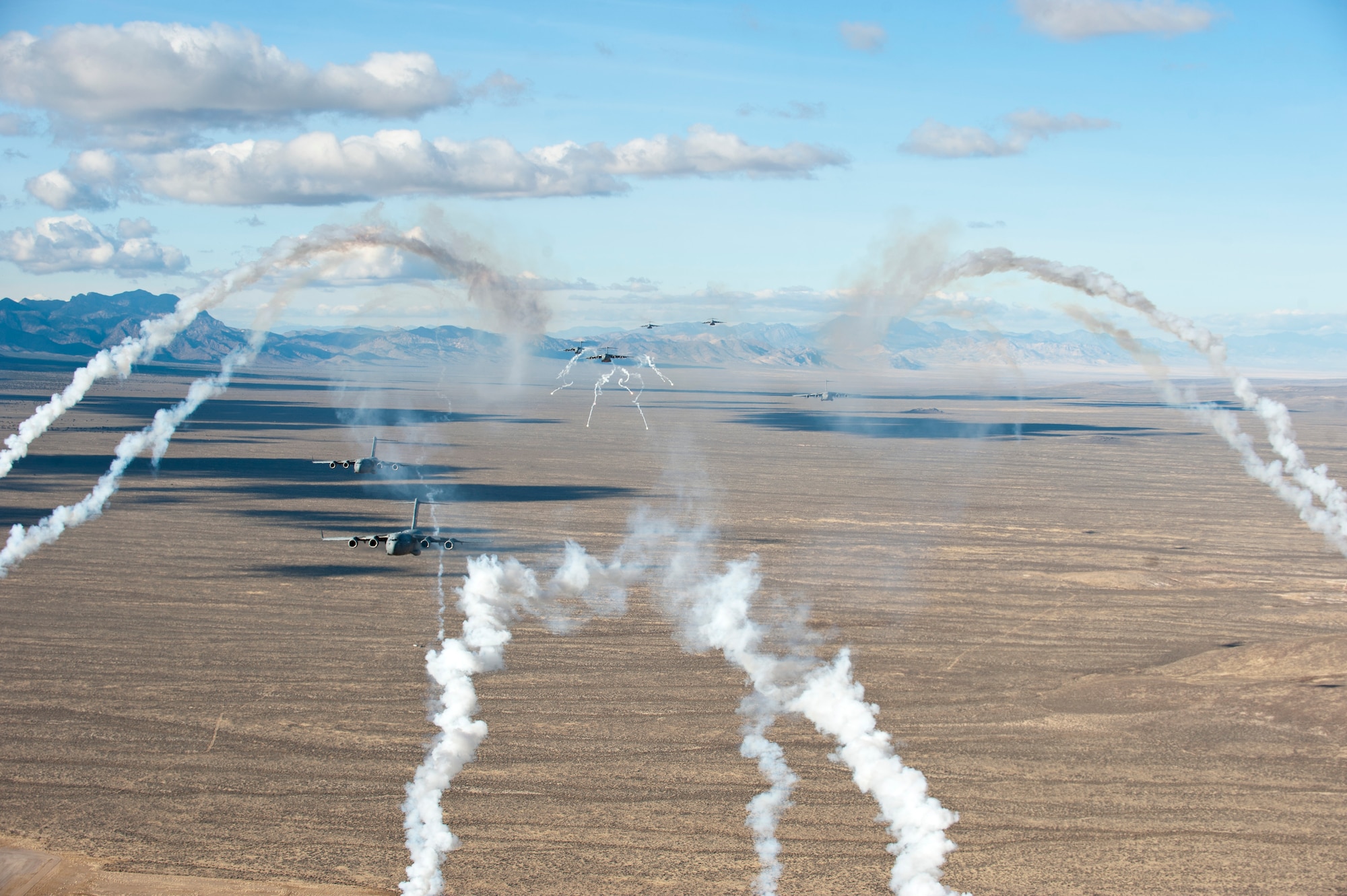 U.S. Air Force C-17 Globemaster IIIs deploy flares while flying over the Nevada Test and Training Range while participating in the U.S. Air Force Weapons School's Joint Forcible Entry Exercise 14B Dec. 6, 2014. When USAFWS students graduate as weapons officers, they will go back to their units and share that knowledge and their experiences from JFEX, to better prepare the Air Force operate in any contingency. (U.S. Air Force photo by Senior Airman Thomas Spangler)