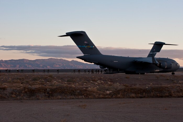 Paratroopers assigned to 3rd Brigade Combat Team, 82nd Airborne Division, Fort Bragg, N.C., make their way a rally point during the Joint Forcible Entry Exercise on the Nevada Test and Training Range, Dec. 6, 2014. More than 100 paratroopers jumped from multiple C-17 Globemaster IIIs and C-130 Hercules as part of training for the USAFWS training to tactically deliver and recover combat forces via air drops and combat landings on an unimproved landing strip. (U.S. Air Force photo by Staff Sgt. Victoria Sneed)