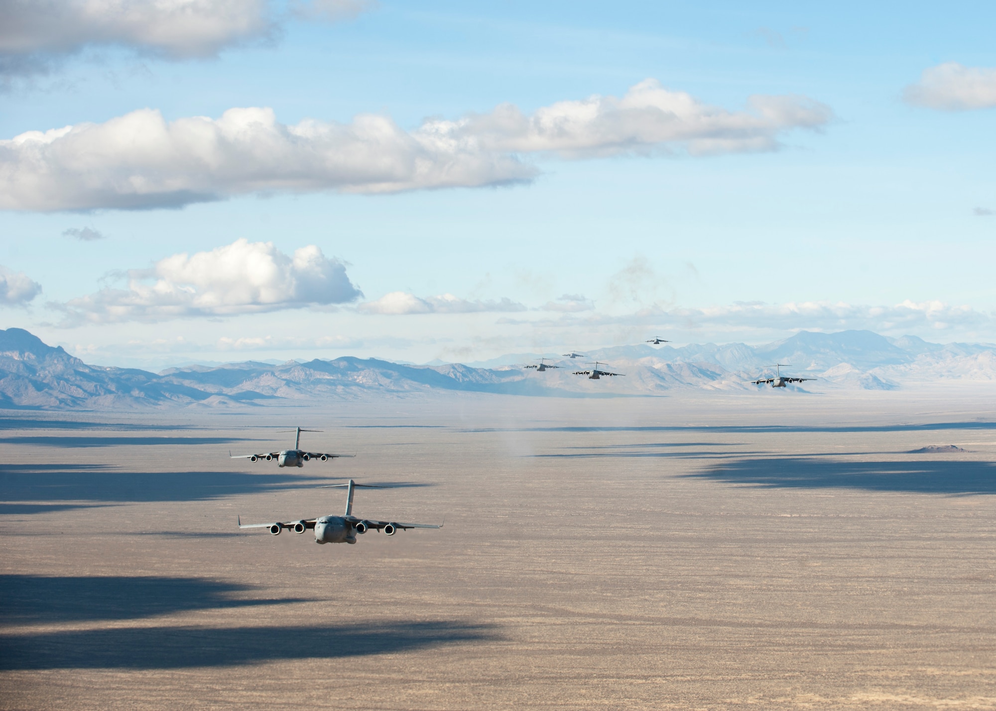 A formation of U.S. Air Force C-17 Globemaster IIIs fly over the Nevada Test and Training Range to participate in the U.S. Air Force Weapons School's Joint Forcible Entry Exercise 14B Dec. 6, 2014. Students participating in JFEX must synchronize aircraft movements from geographically separated bases, command large formations of dissimilar aircraft in high-threat airspace, and tactically deliver and recover combat forces via air drops and combat landings on an unimproved landing strip. (U.S. Air Force photo by Senior Airman Thomas Spangler)