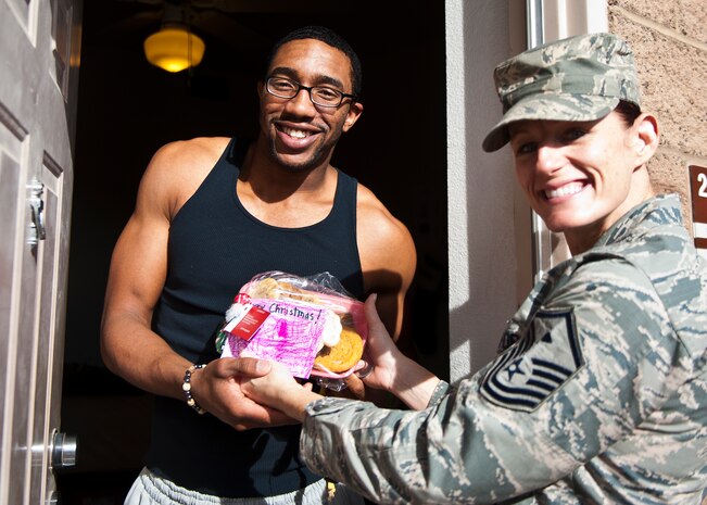 Airman 1st Class Devonte Robinson, 99th Medical Support Squadron (left) receives a freshly baked cookie tray from Master Sgt. Sharon Tyree, 99th MDSS first sergeant, during the base cookie drive on Nellis Air Force Base, Nev., Dec. 8. The cookies were sorted by the Nellis Spouses’ Club and volunteers, then delivered by first sergeants to Airmen from their squadrons living in the dorms. (U.S. Air Force photo by Airman 1st Class Mikaley Towle)