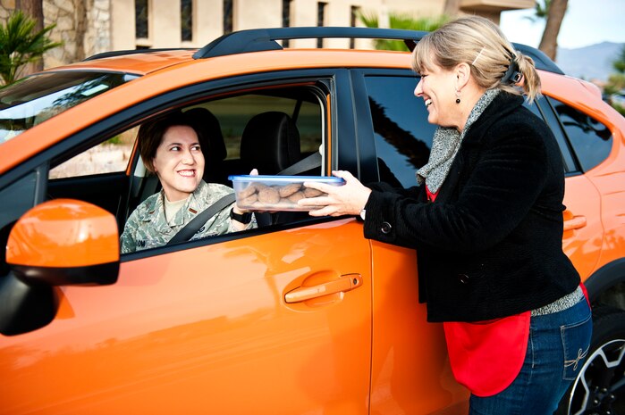2nd Lt. Chelsea Froom, Joint Electromagnetic Preparedness for Advanced Combat analyst, drops off home baked cookies to a member of the Nellis Area Spouses’ Club during the base-wide cookie drive at the chapel on Nellis Air Force Base, Nev., Dec. 8, 2014. More than 15,000 cookies were baked and donated by installation members and delivered to all dormitory residents as a way of increasing morale amongst Airmen living on base during the holiday season. (U.S. Air Force photo by Airman 1st Class Mikaley Towle)