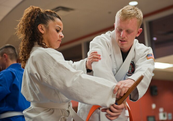 Robert McIntosh assists his wife Judith in her hand placement while learning to disarm an assailant during the Nesei Bujutsu class at the Warrior Fitness Center on Nellis Air Force Base, Nev., Dec. 9, 2014. Student are instructed how to apply pressure to certain joints to compel opponents to go where they what or disarm an attacker. (U.S. Air Force photo by Staff Sgt. Victoria Sneed)