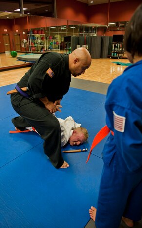 Renshi DeAndre Scott (black gi) instructs students on simple pressure can disarm an attacker during the Nesei Bujutsu class at the Warrior Fitness Center on Nellis Air Force Base, Nev., Dec. 9, 2014. Students are taught different holds and pressure points that cause assailants to drop their weapon while also subduing them.. (U.S. Air Force photo by Staff Sgt. Victoria Sneed)