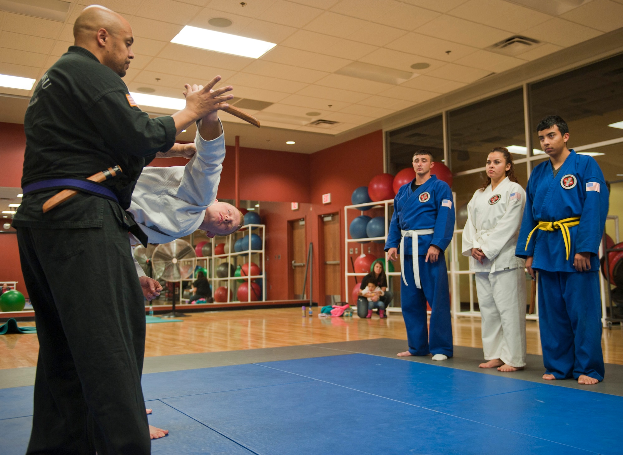 Renshi DeAndre Scott (black gi) instructs students to disarm and attacker during the Nesei Bujutsu class at the Warrior Fitness Center on Nellis Air Force Base, Nev., Dec. 9, 2014. Families attend the class to learn discipline and self-defense from armed and unarmed attackers as part of the class. (U.S. Air Force photo by Staff Sgt. Victoria Sneed)