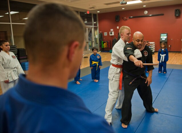 Renshi DeAndre Scott (black gi) instructs students on holds to disarm an attacker during the Nesei Bujutsu class at the Warrior Fitness Center on Nellis Air Force Base, Nev., Dec. 9, 2014. Students are taught to use holds and pressure points to subdue and disarm attackers, regardless of size. (U.S. Air Force photo by Staff Sgt. Victoria Sneed)
