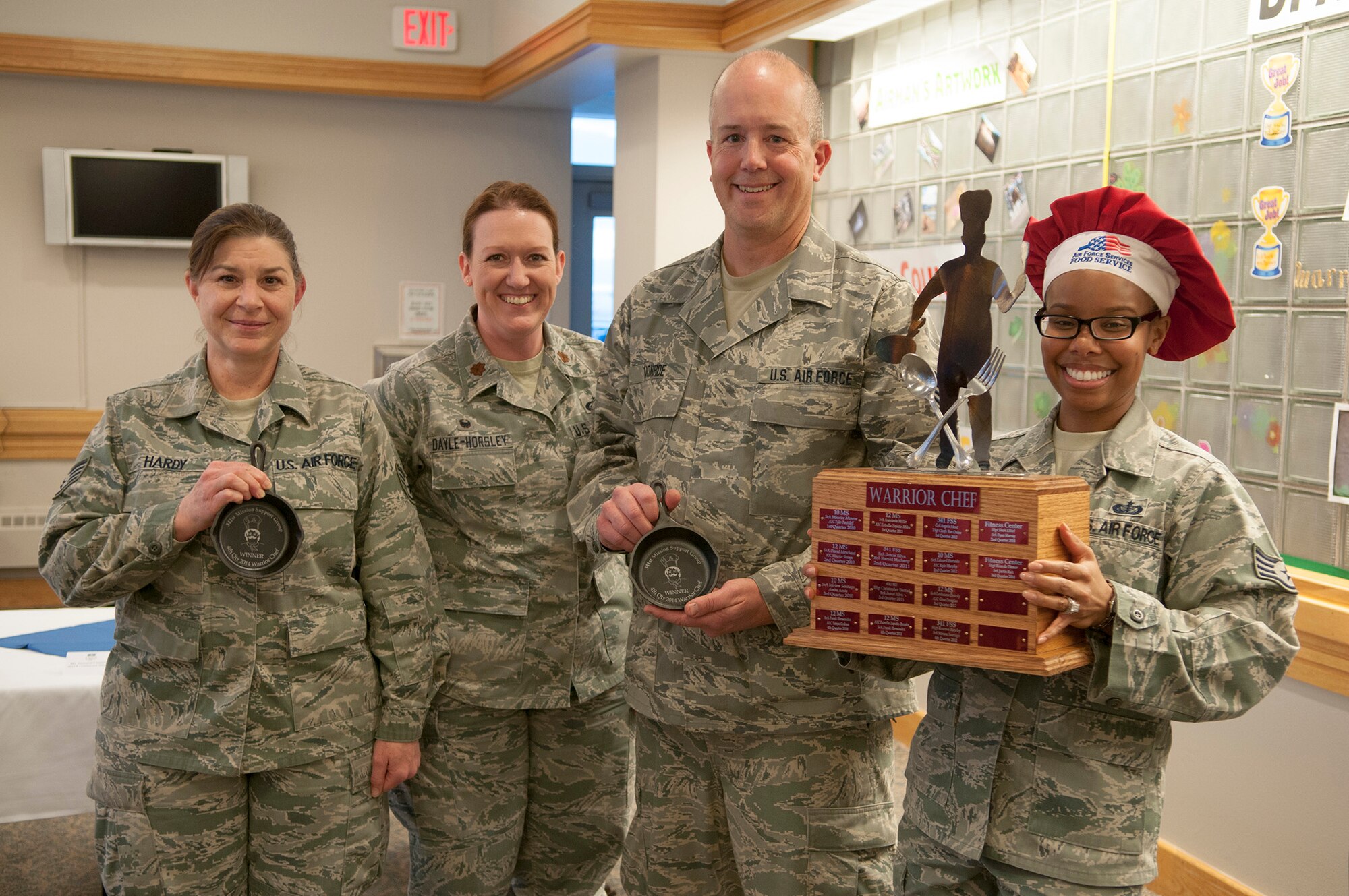 Staff Sgts. Sara Hardy and Todd Monroe, the Fourth Quarter Warrior Chef Competition’s winning team, pose with their trophy skillets Dec. 4 at the Elkhorn Dining Facility. Both are from the 120th Force Support Squadron, Montana Air National Guard. Standing with them are Maj. Karen Dayle-Horsley, 341st Force Support Squadron commander, and event coordinator Staff Sgt. Amber Moore, 341st FSS noncommissioned officer in charge of missile alert feeding operations.  (U.S. Air Force photo/Tech. Sgt. Christina Perchine)