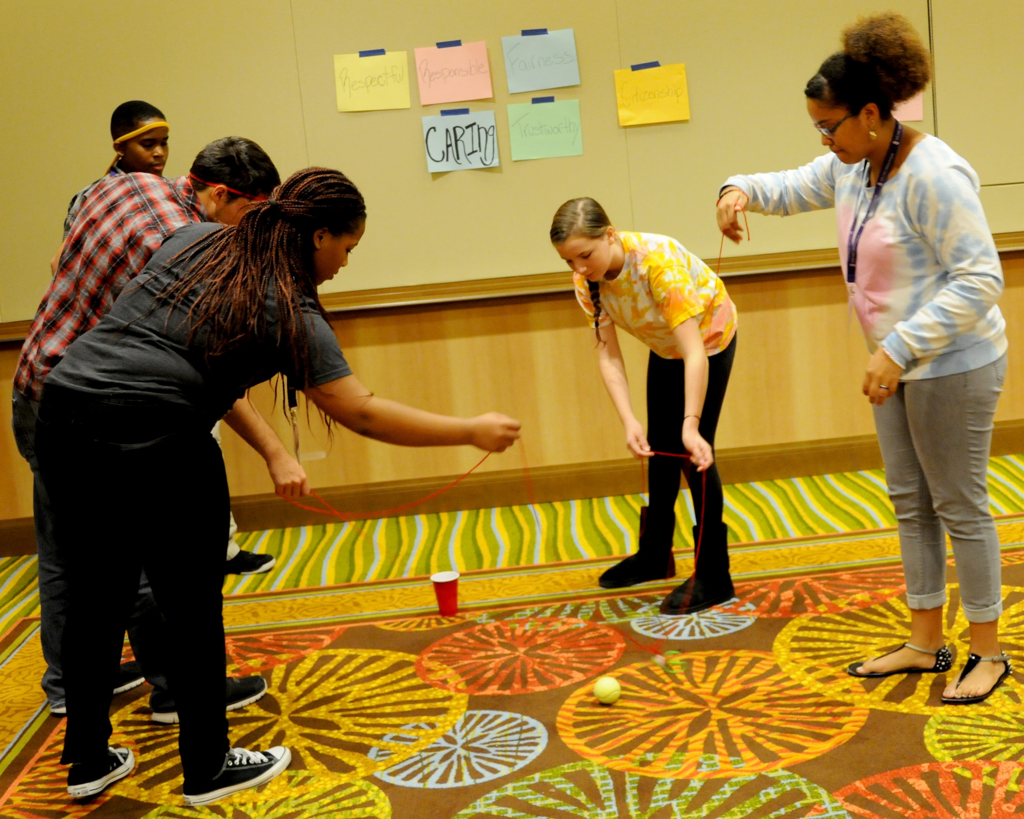 Teenagers work together as a team to try to navigate a ball into a cup using only yarn during an Air Force Reserve Yellow Ribbon Program event Nov. 21-23 in Orlando, Florida. Yellow Ribbon events help provide reservists and their loved ones access to the resources they need to help booster morale and welfare while maintaining resiliency during all stages of a deployment. (U.S. Air Force photo by Master Sgt. Shanda De Anda)