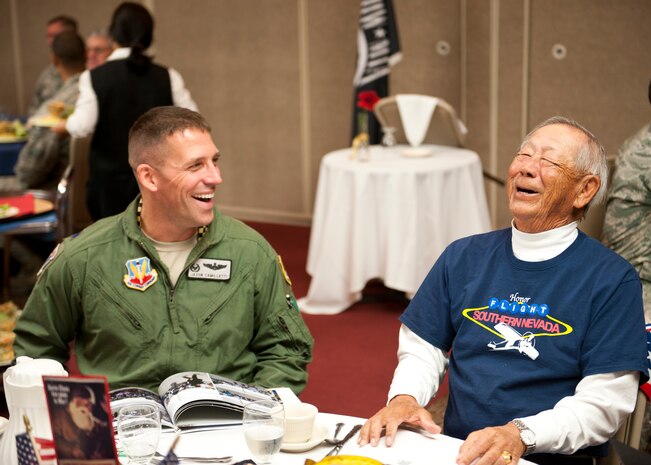 Lt. Col. Jason Camilletti, 57th Operations Support Squadron commander, shares a laugh with Ed Lun, a retired Air Force pilot and veteran of World War II, Korea and Vietnam, at the Southern Nevada Honor Flight WWII vets lunch at the Club at Nellis Air Force Base, Dec. 5, 2014. Lun was 15 years old at the time of the Pearl Harbor attack. He joined the U.S. Marine Corps at age 17 and served in WWII. The luncheon was held to honor WWII veterans as well as veterans of other wars. (U.S. Air Force photo by Senior Airman Thomas Spangler)