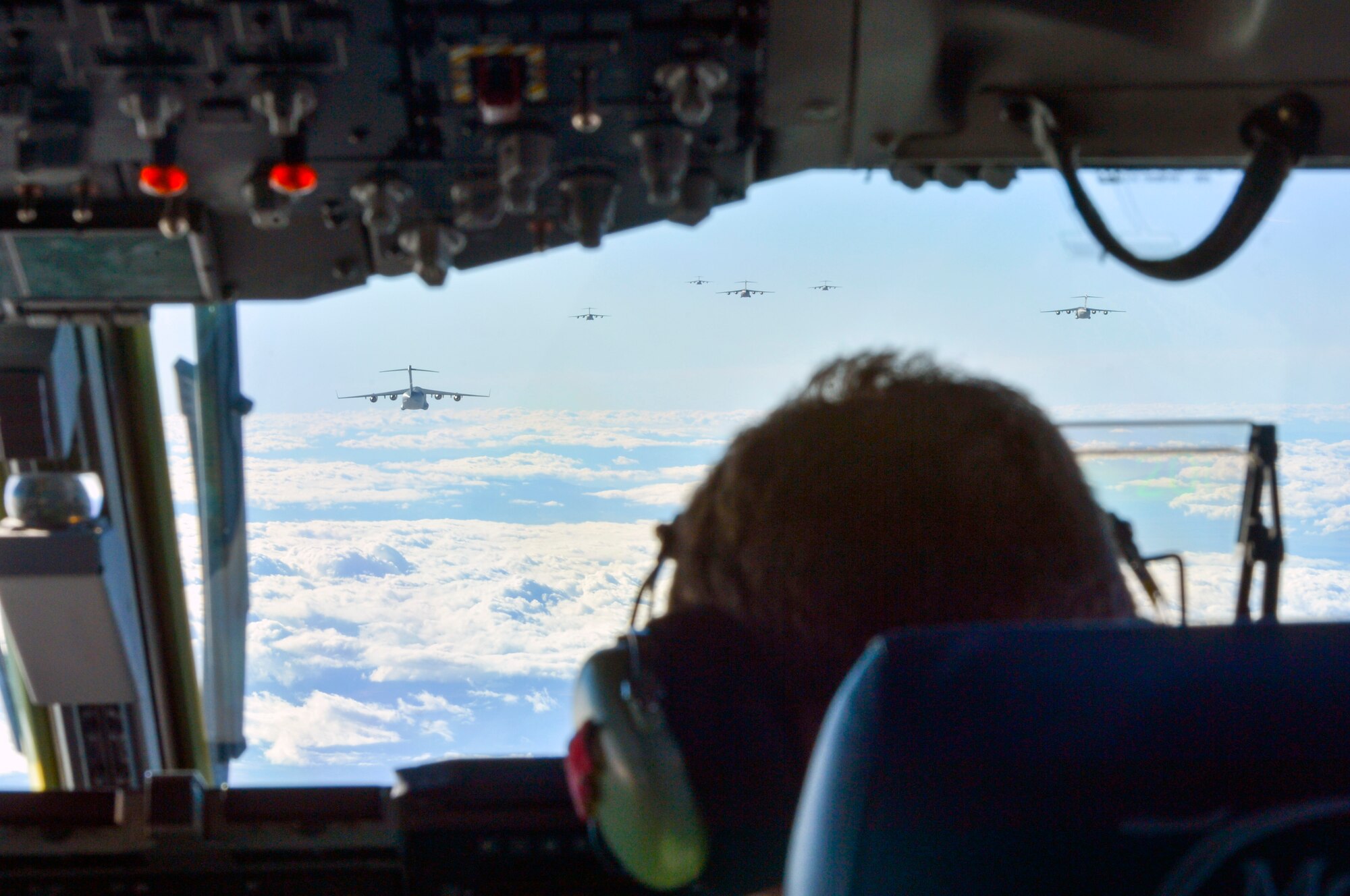 Capt. Justin Jarrell, 7th Airlift Squadron pilot, positions a C-17 Globemaster III aircraft in formation with other C-17’s from bases across the United States Dec. 6, 2014, before a joint forcible entry exercise near the Keno drop zone, Nev. Entry operations enable broader strategic goals, such as removing threats to the free flow of commerce, aggression, or when necessary, defeating enemy forces on foreign territory. (U.S. Air Force photo/Staff Sgt. Russ Jackson) 