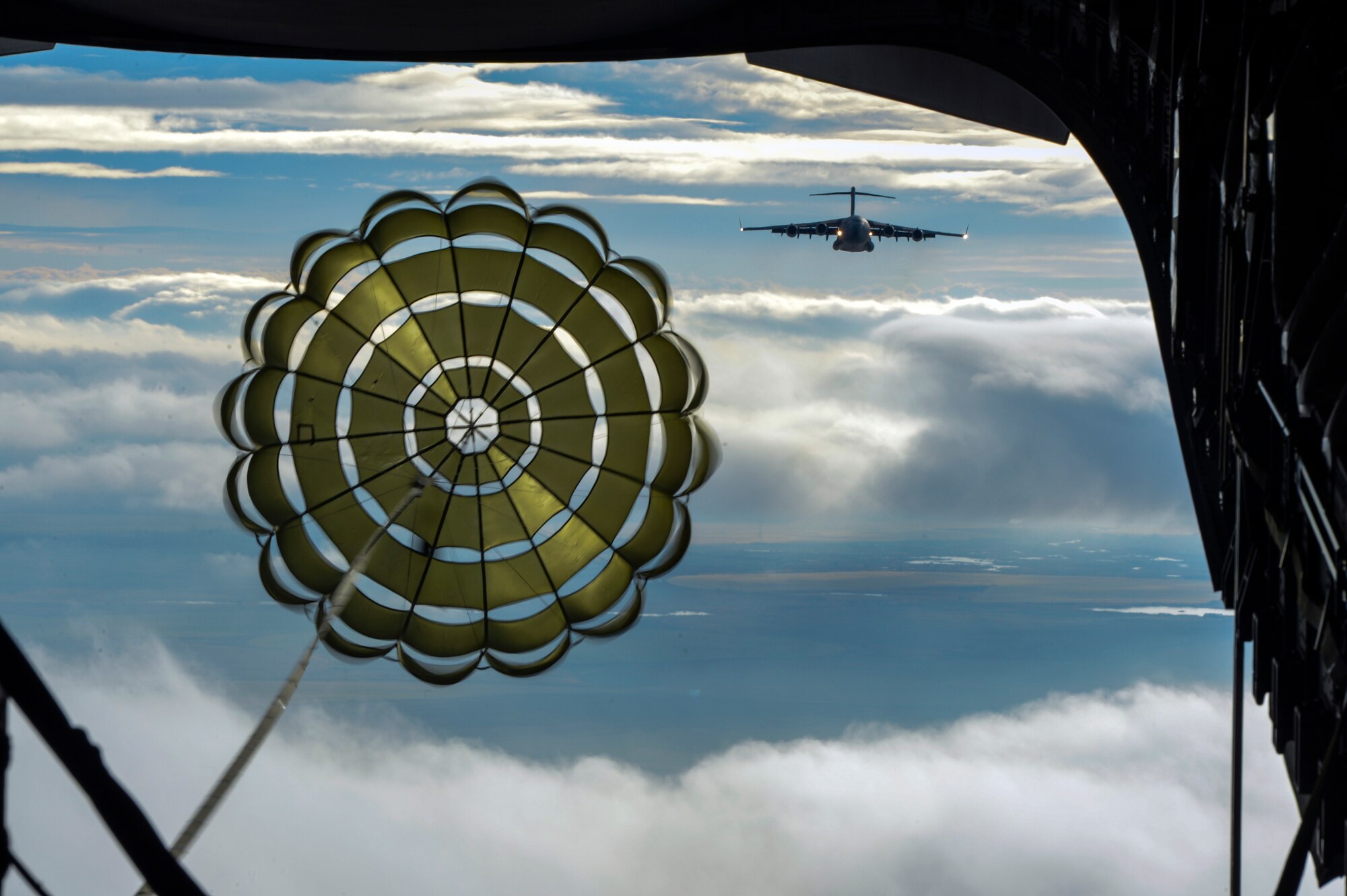 A parachute from a heavy container delivery system opens before being air dropped to forces on the ground during the simulated Rainier War before a joint forcible entry exercise Dec. 6, 2014, over the Rainier drop zone, Wash. Joint Base Lewis-McChord augmented this Air Force level JFE exercise however the “war” was developed by students from the 62nd Wing Tactics and Intel weapons course.  (U.S. Air Force photo/Staff Sgt. Russ Jackson)