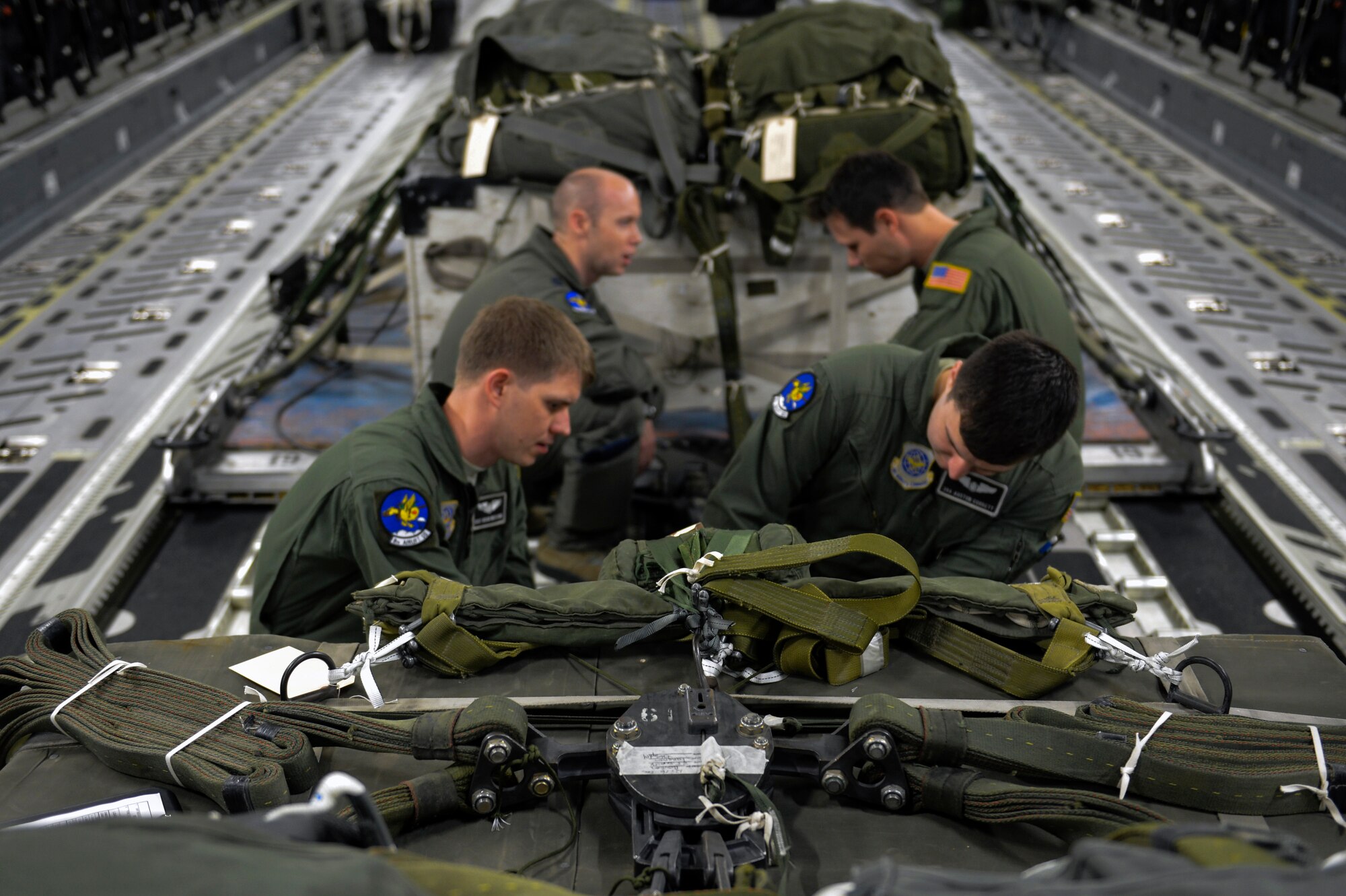 Staff Sgt. Brian Whitcomb (left), and Senior Airman Auston Corbett (right), 8th Airlift Squadron loadmasters, inspect heavy container delivery system air drop cargo Dec. 6, 2014, at Joint Base Lewis-McChord in support of a joint forcible entry exercise. The aircrew released the two air drop bundles over the Rainier drop zone during the fabricated Rainier War. (U.S. Air Force photo/Staff Sgt. Russ Jackson)