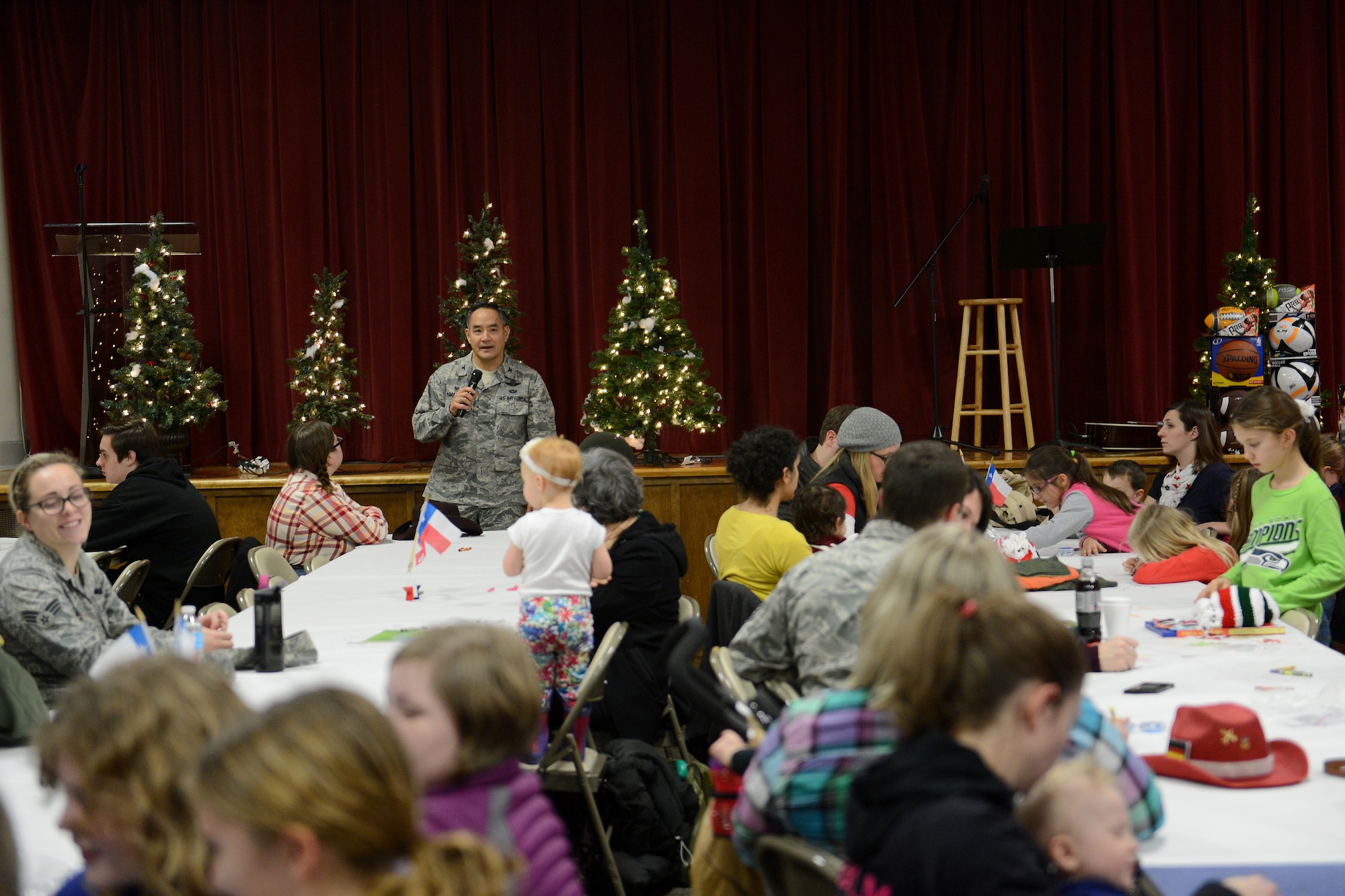 Col. David Kumashiro, 62nd Airlift Wing commander, gives a few words to Airmen and families Dec. 8, 2014, during a deployed family dinner at the Chapel Support Center on Joint Base Lewis-McChord, Wash. During the event, families and Airmen ate food, won prizes through raffle tickets and listened to a live guitar act. (U.S. Air Force photo/Airman 1st Class Keoni Chavarria)