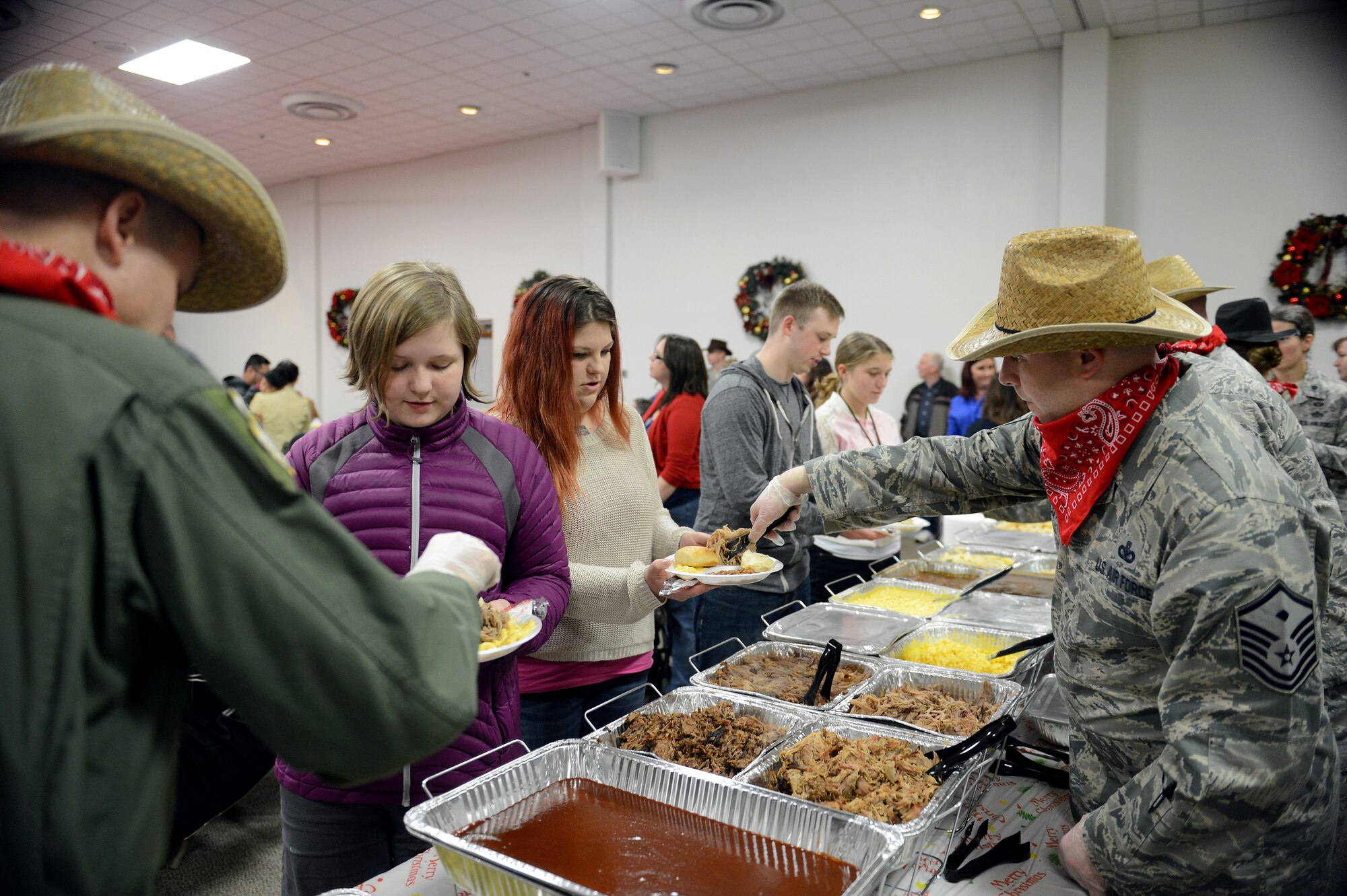 Commanders and first sergeants serve food to families Dec. 8, 2014, during a deployed family dinner at the Chapel Support Center on Joint Base Lewis-McChord, Wash. This year, there was a Texas theme throughout the dinner and some Airmen wore cowboy like hats along with red bandanas. (U.S. Air Force photo/Airman 1st Class Keoni Chavarria)