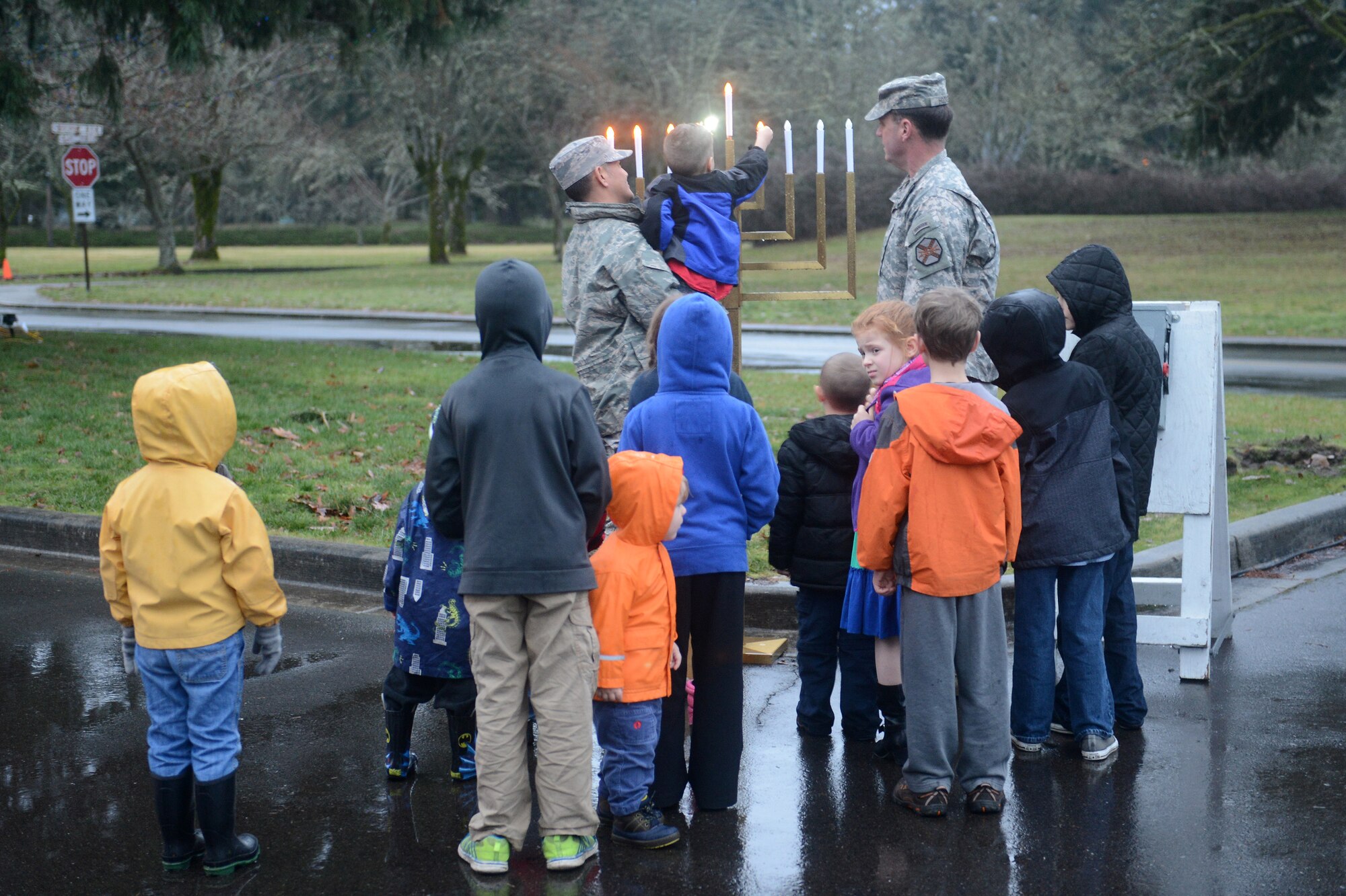 Col. David Kumashiro (left), 62nd Airlift Wing commander, holds a child to turn on a light of the Menorah Dec. 8, 2014, during the McChord Field Annual Tree Lighting ceremony at Joint Base Lewis-McChord, Wash. Each candle light on the Menorah was lit by a child in celebration of Hanukkah. (U.S. Air Force photo/Airman 1st Class Keoni Chavarria)