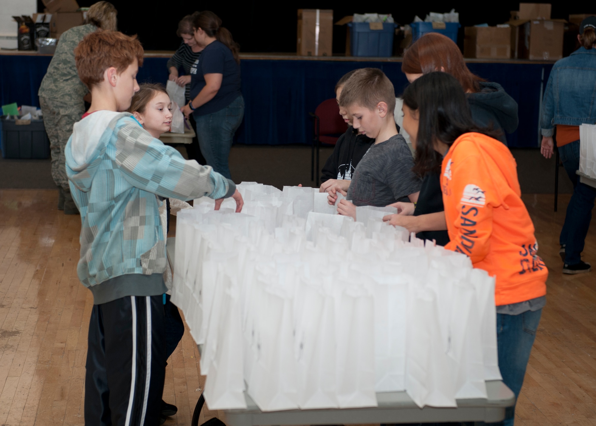 Children from Holloman Middle School are briefed by military spouses and volunteers before helping to package cookies for the annual holiday cookie drive at Holloman Air Force Base, N.M., Dec. 8. Over 1,800 cookies were packaged for all the airmen residing in the dorms on Holloman. (U.S. Air Force photo by Senior Airman Class Daniel Liddicoet/Released)