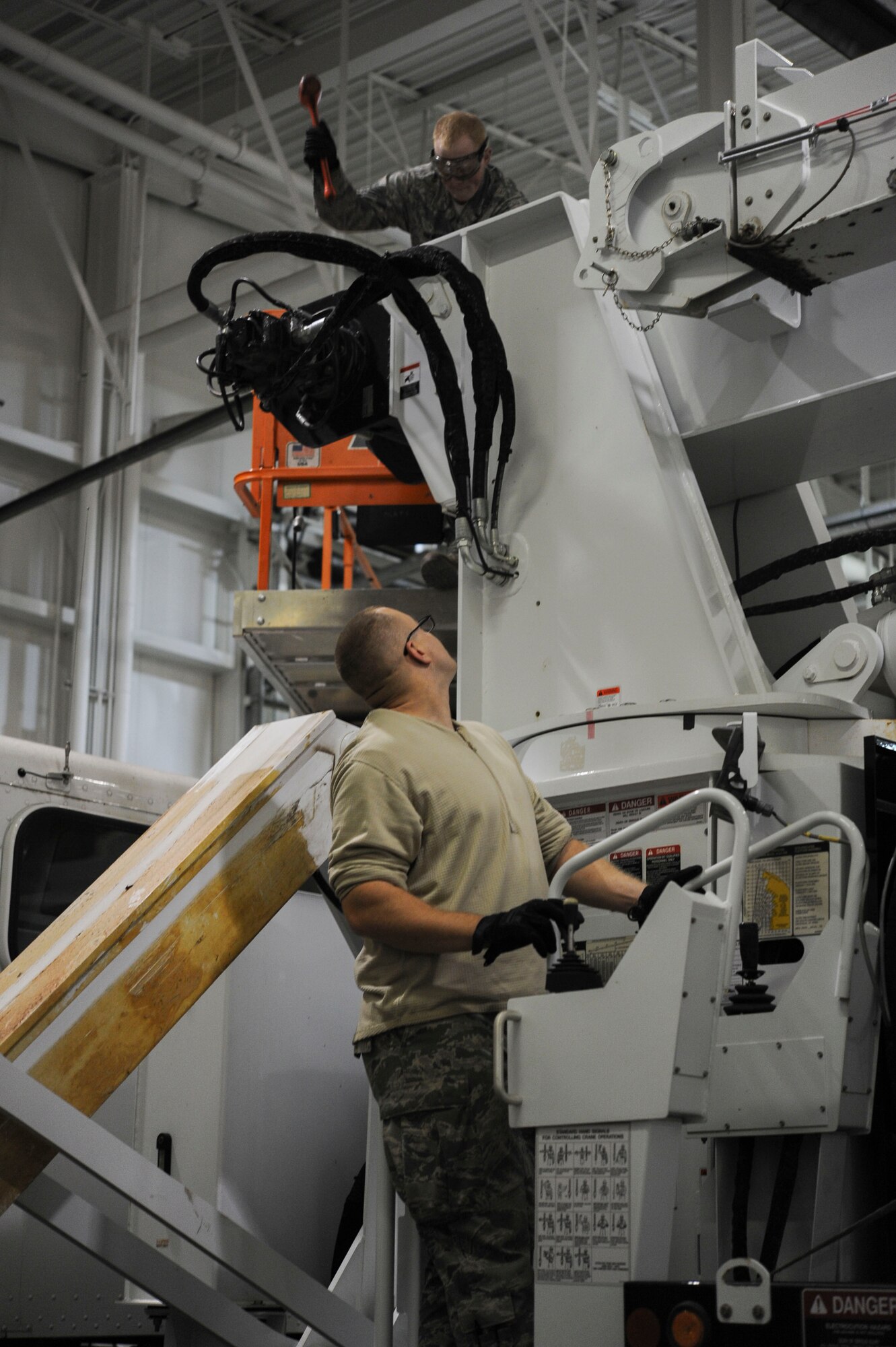 Senior Airman Brandon Gilmore, 91st Missile Operations Squadron mechanical and pneudraulics section technician, uses a hammer to reattach a new cable to a crane as Senior Airman Brandon Lade, 91st MOS MAPS technician, calls out instructions on Minot Air Force Base, N.D. Oct. 30, 2014. All of the technicians involved kept a constant dialog to ensure tnothing was overlooked and that the maintenance was completed safely. (U.S. Air Force photo/Senior Airman Stephanie Morris)